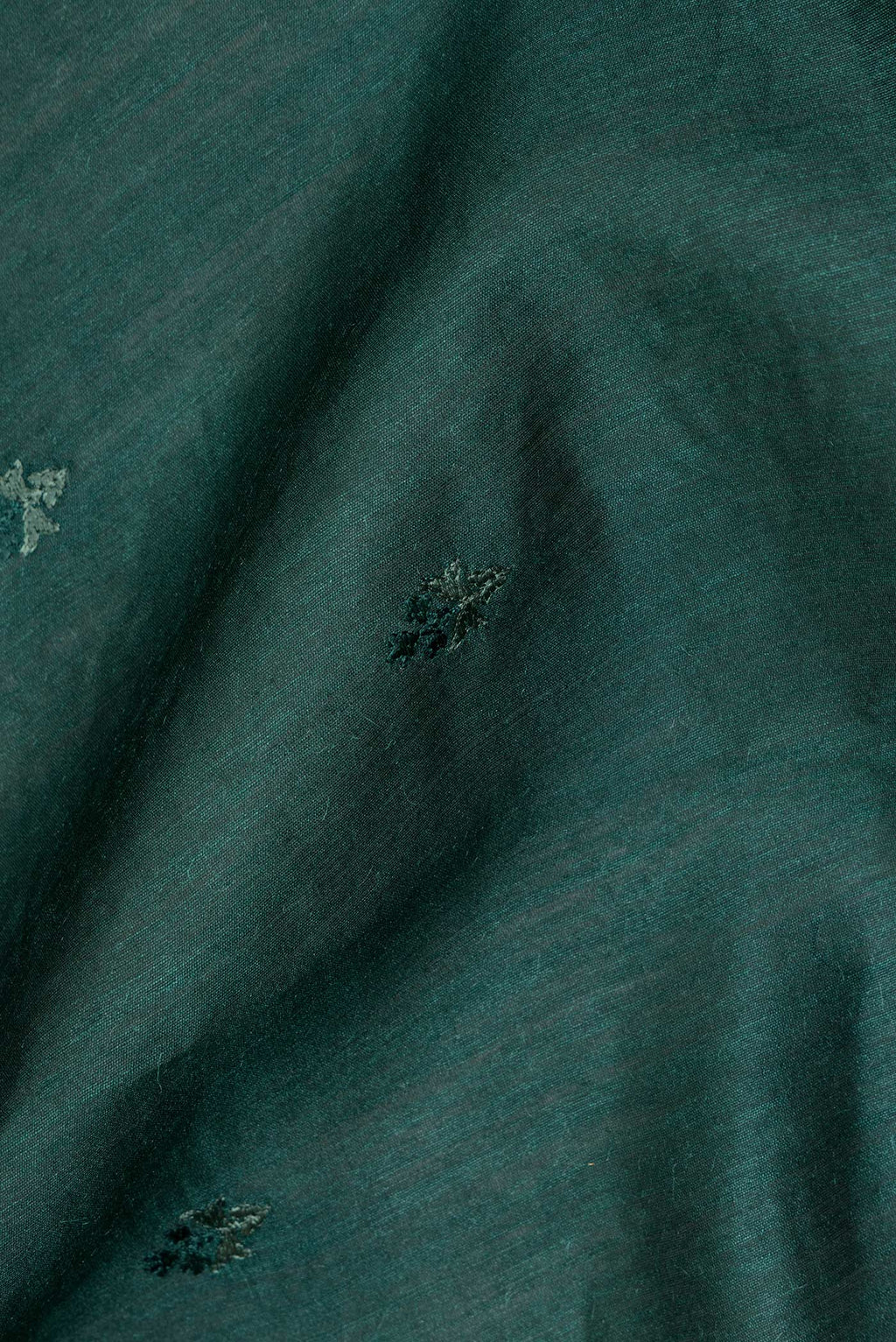 Close up of Bottle Green Tussar Saree with Embroidered on the body and Embroidered Border.  displaying folds