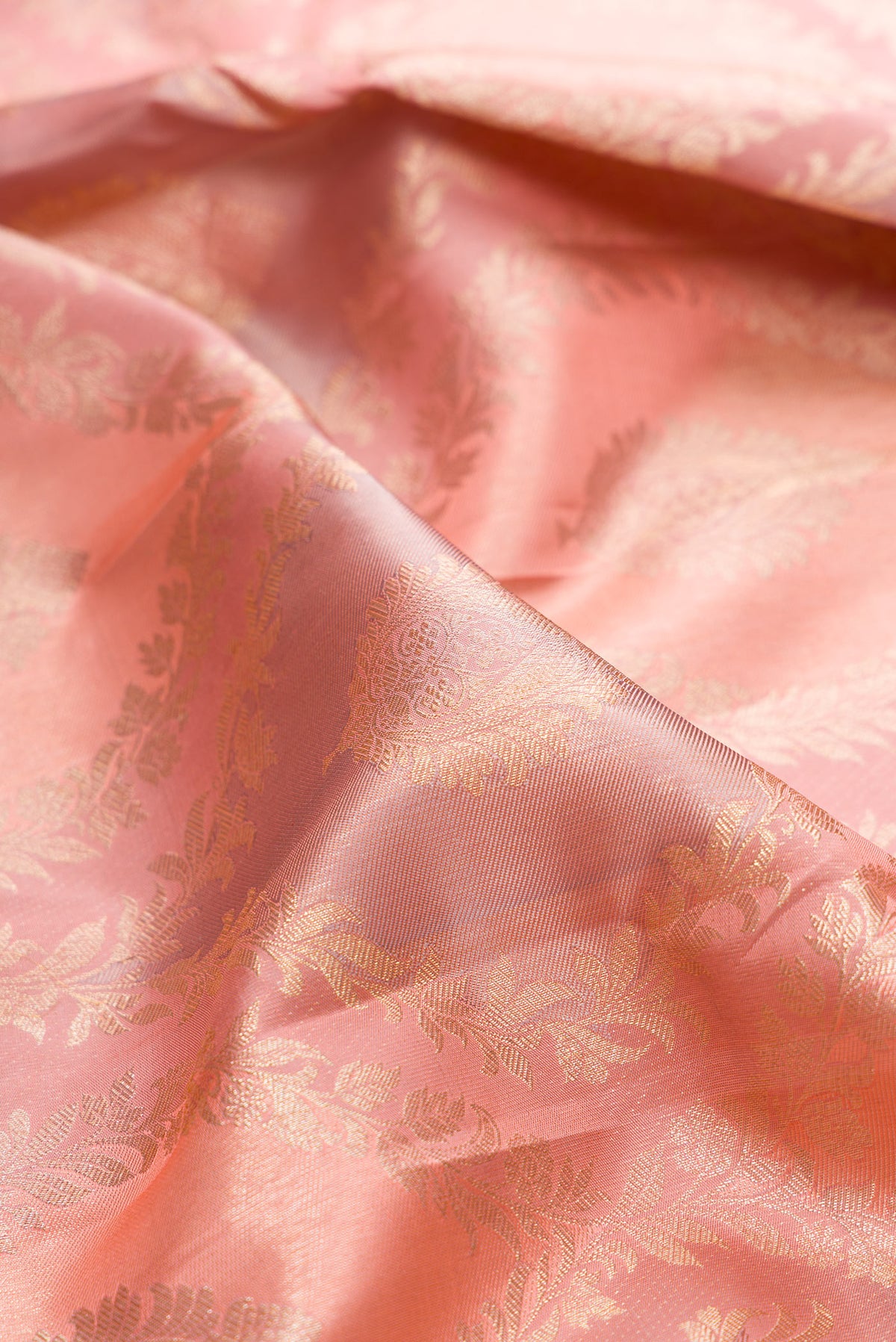 Close up of Pure Silk Rose Gold Dual Tone Kanjivaram Saree with Zari Brocade on the body and Zari Border.  displaying folds