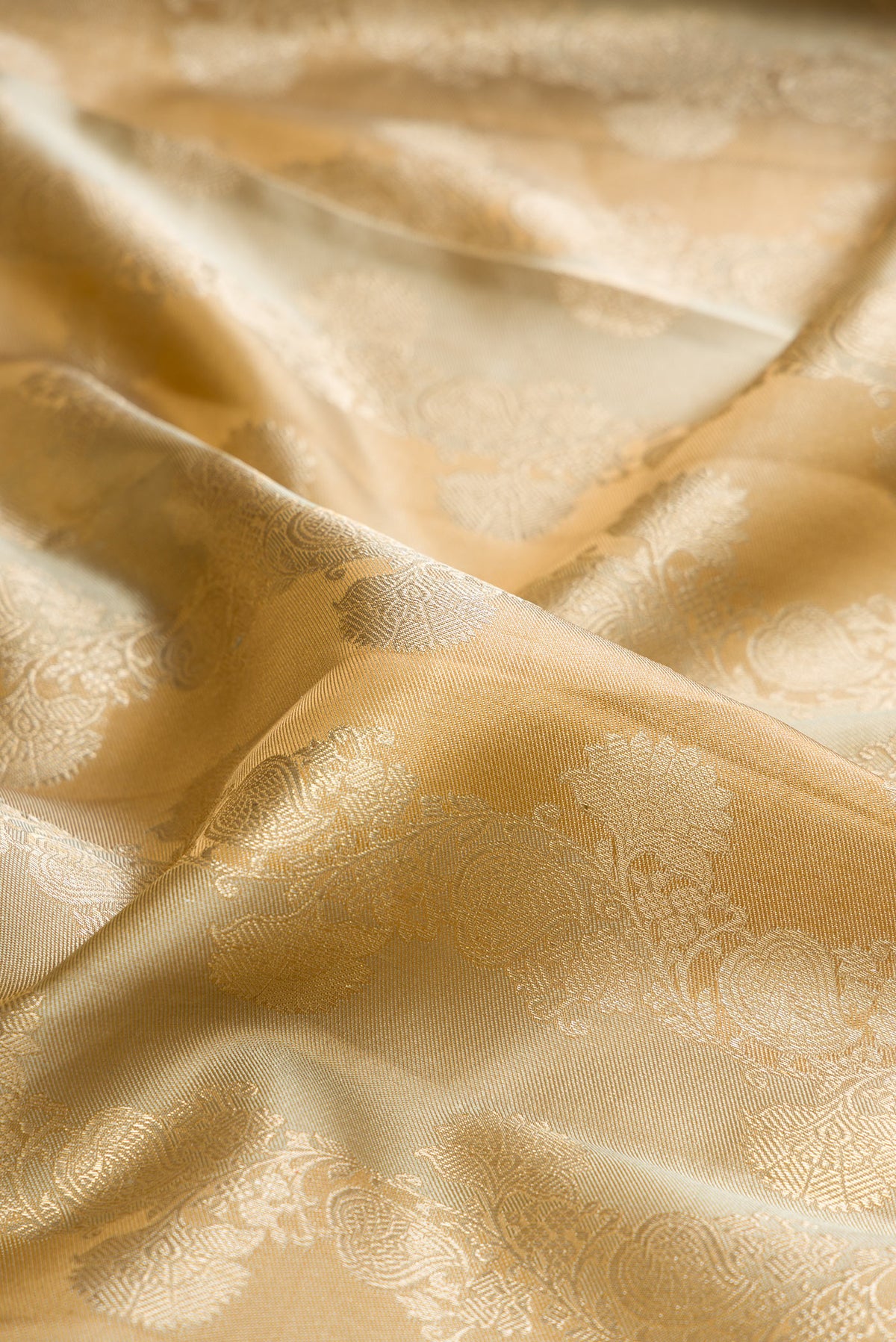 Close up of Pure Silk Dark Beige Dual Tone Kanjivaram Saree with Zari Brocade on the body and Zari Border.  displaying folds