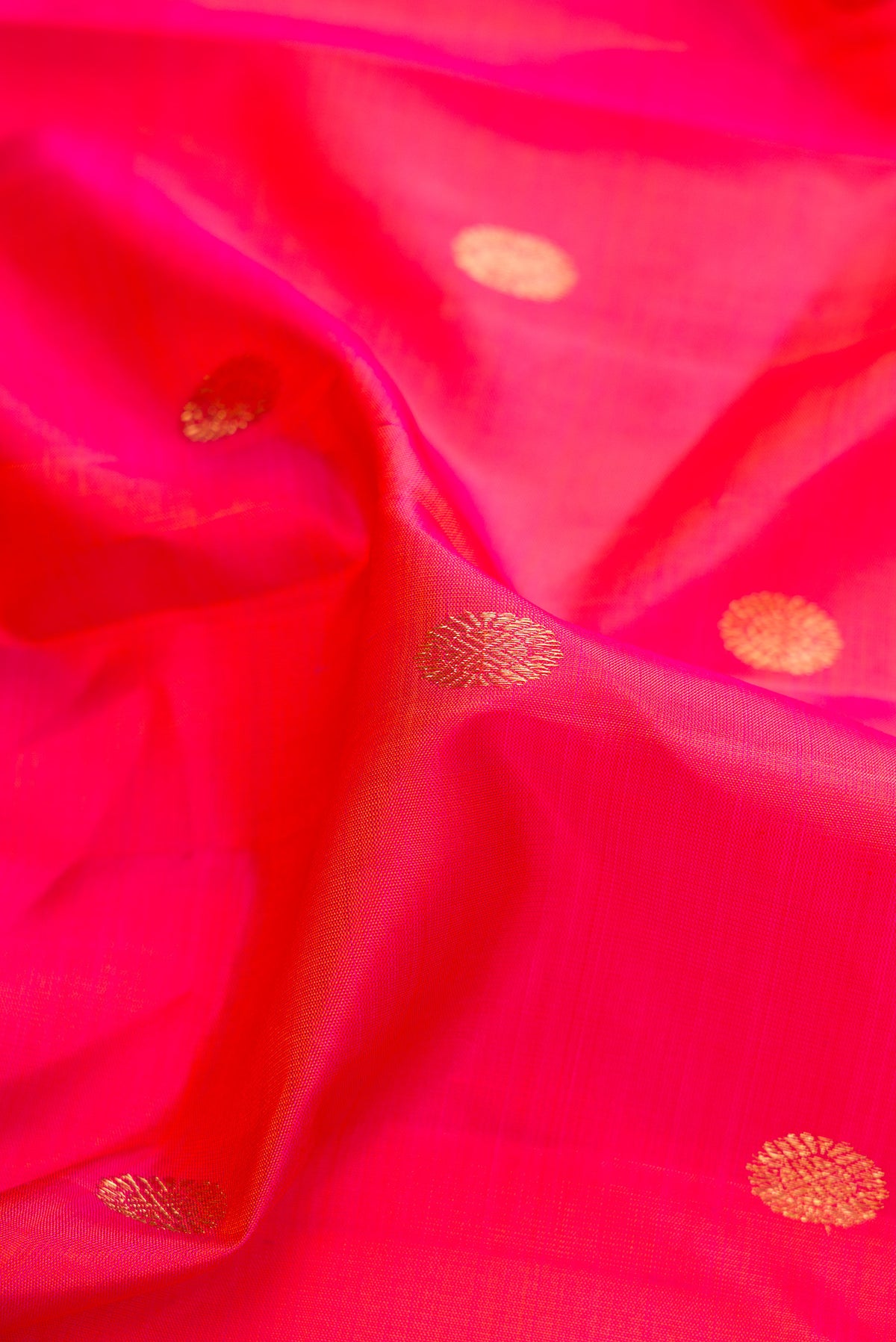 Close up of Pure Silk Coral Dual Tone Kanjivaram Saree with Zari Butta on the body and Zari Border.  displaying folds