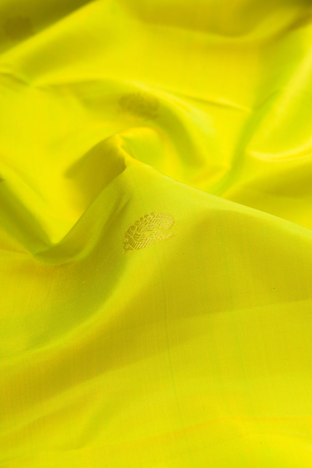 Close up of Pure Silk Parrot Green Kanjivaram Saree with Zari Butta on the body and Zari Border.  displaying folds