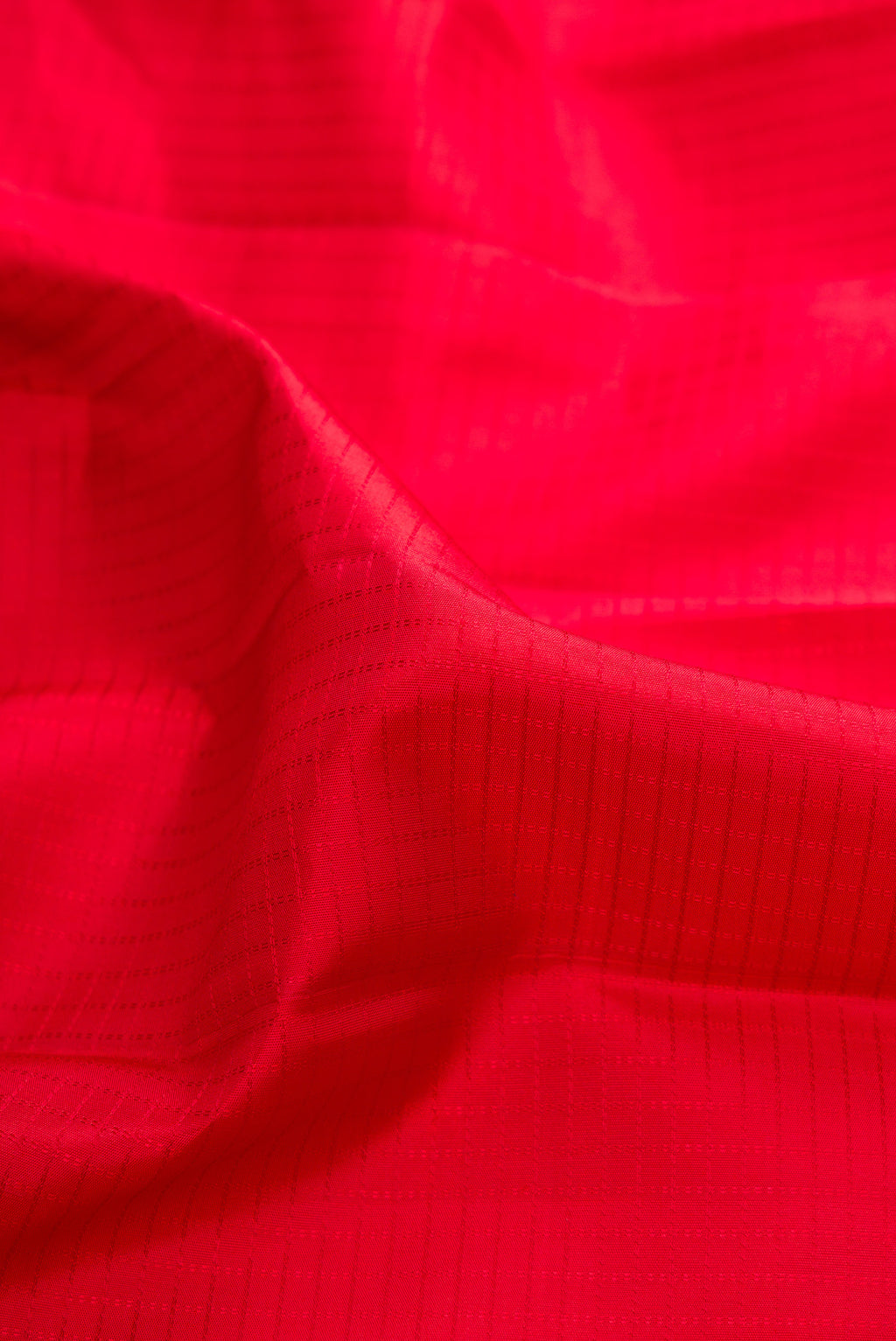 Close up of Pure Silk Red Kanchipuram Saree with Checked design on the body and Zari Border.  displaying folds