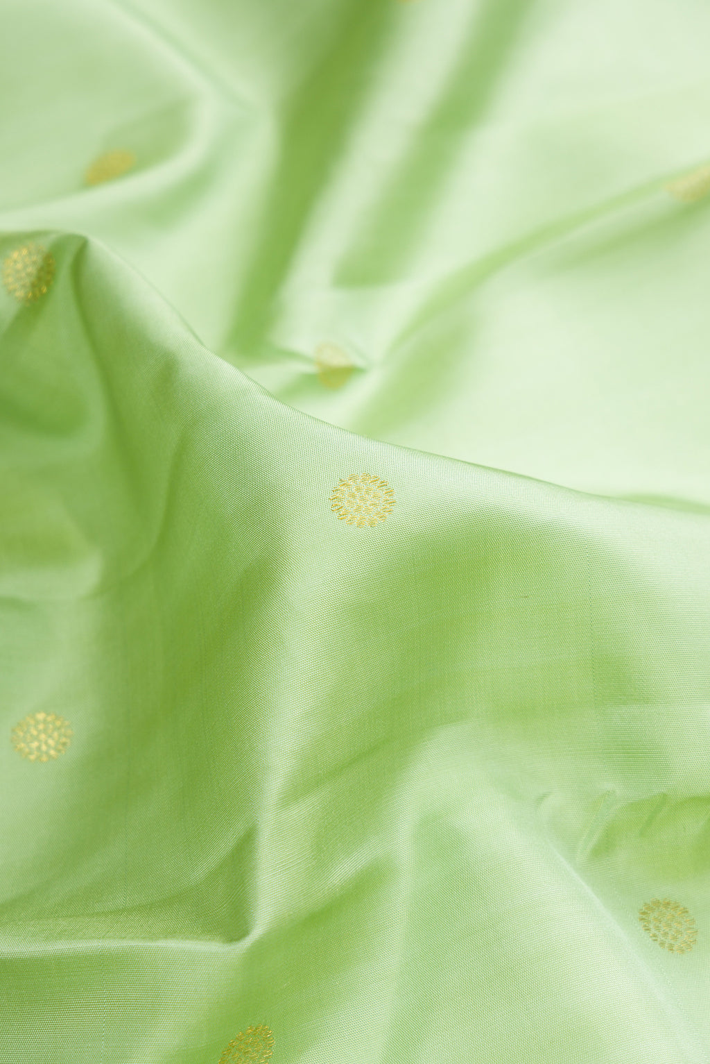 Close up of Pure Silk Pista Green Kanchipuram Saree with Zari Butta on the body and Zari Border.  displaying folds
