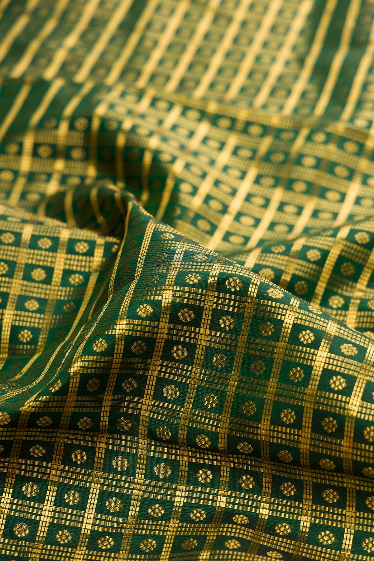 Close up of Pure Silk Bottle Green Kanchipuram Saree with Checked design on the body and Zari Border.  displaying folds