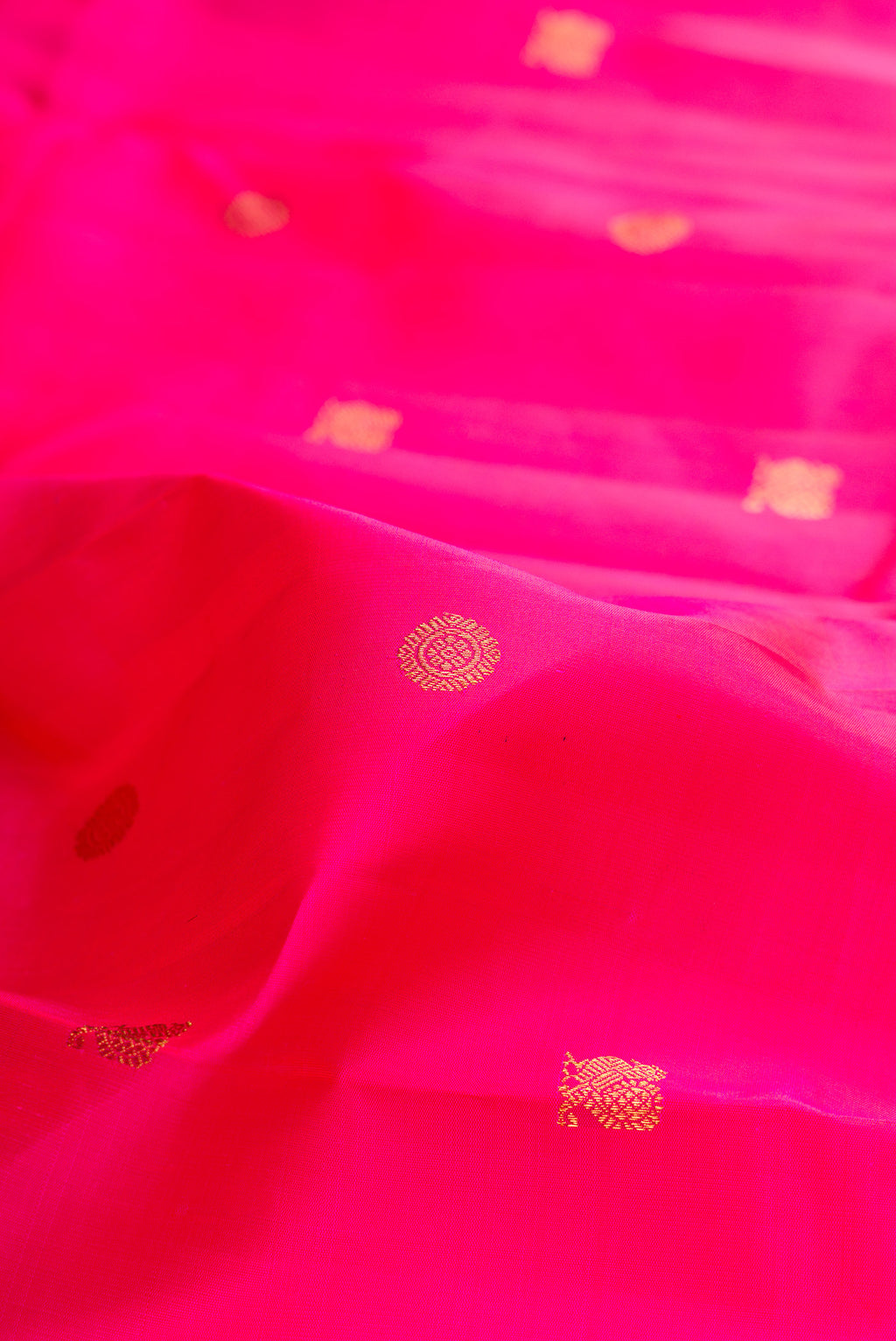 Close up of Pure Silk Pure Zari Rani Pink Kanjivaram Saree with Zari Butta on the body and Zari Border.  displaying folds