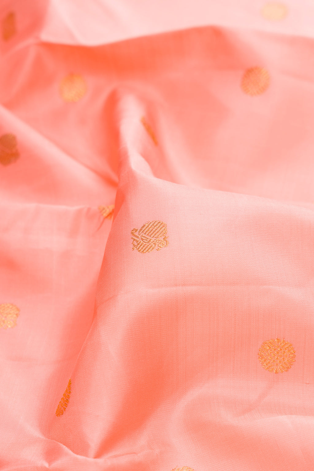 Close up of Pure Silk Pure Zari Peach Kanjivaram Saree with Zari Butta on the body and Zari Border.  displaying folds