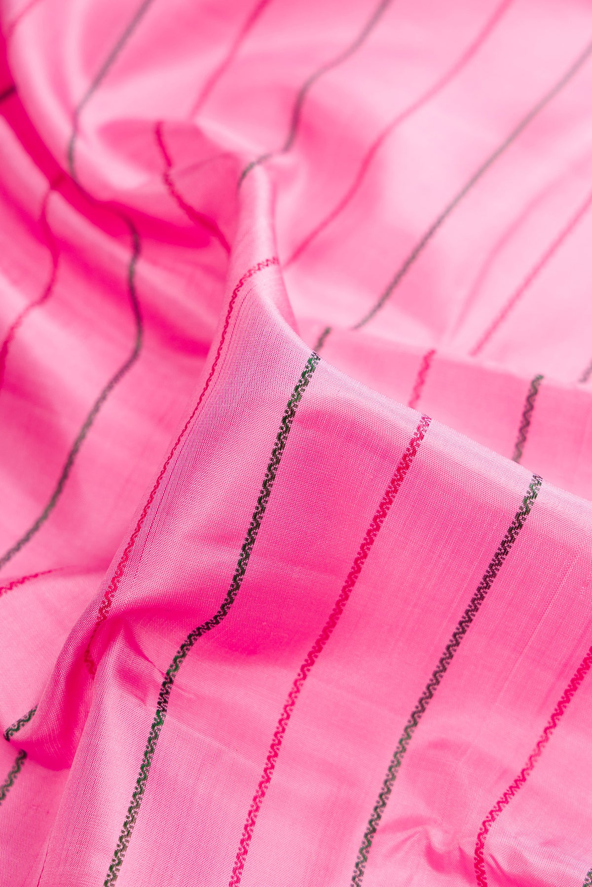 Close up of Pure Silk Rose pink Kanchipuram Saree with Veldhari on the body and Zari Border.  displaying folds
