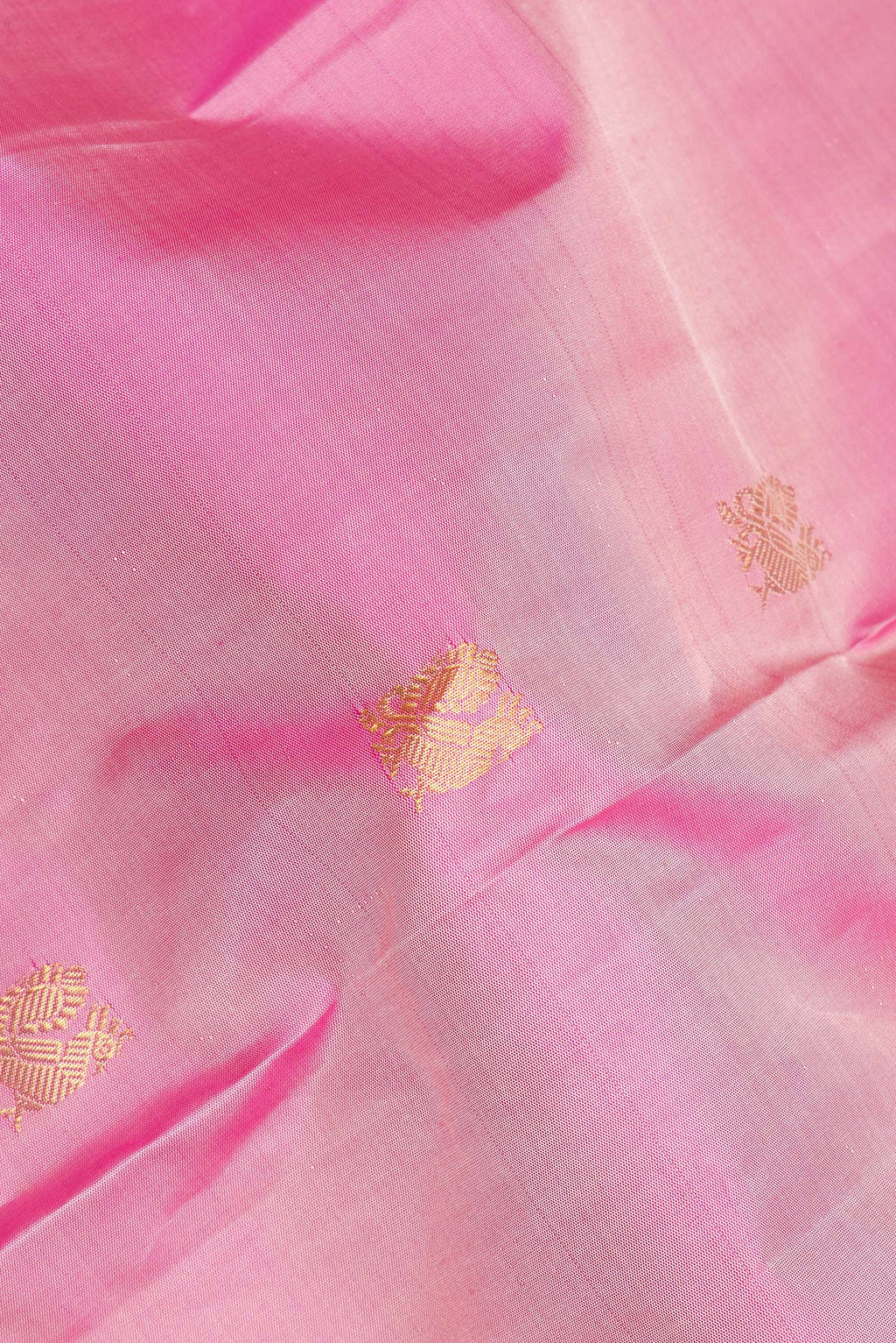 Close up of Pure Silk Rose Gold Dual Tone Kanjivaram Saree with Zari Butta on the body and Zari Border.  displaying folds