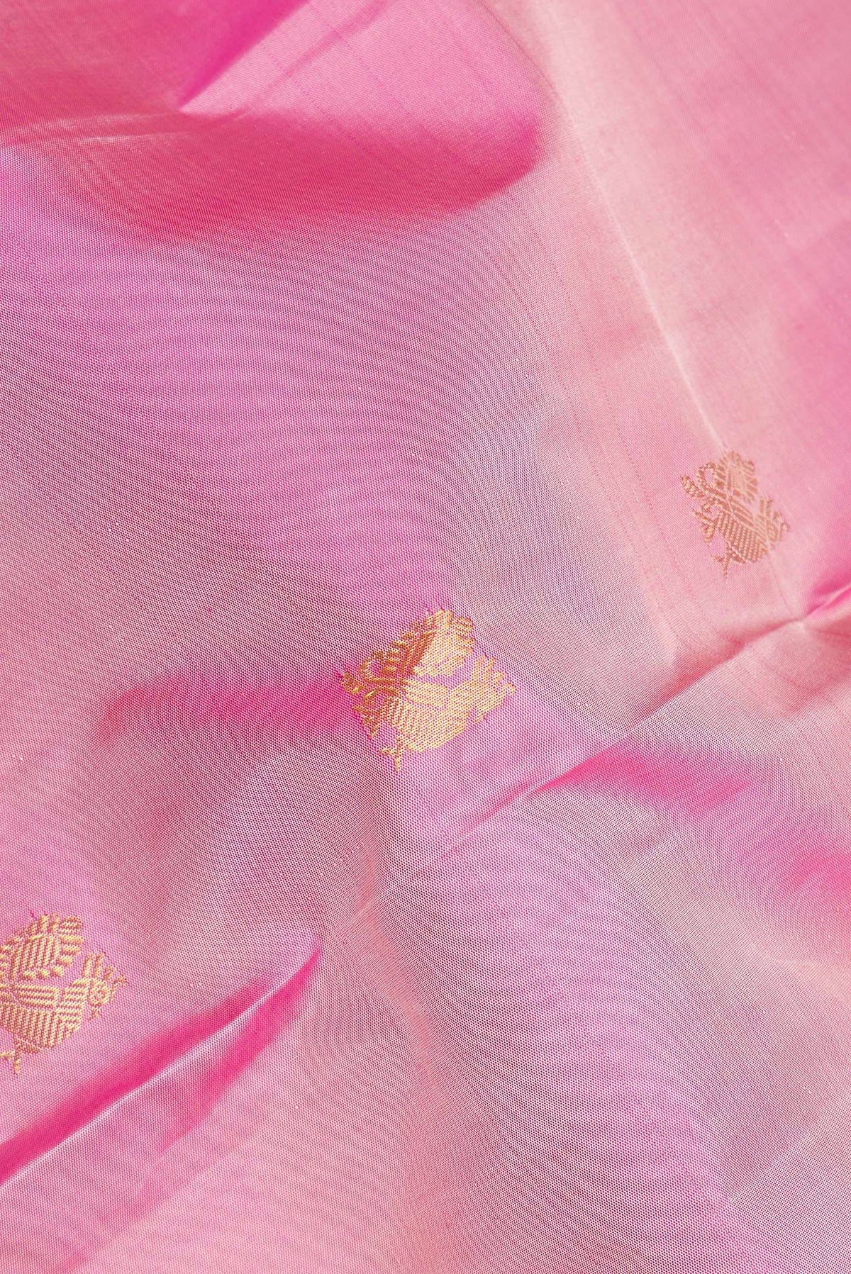 Close up of Pure Silk Rose Gold Dual Tone Kanjivaram Saree with Zari Butta on the body and Zari Border.  displaying folds