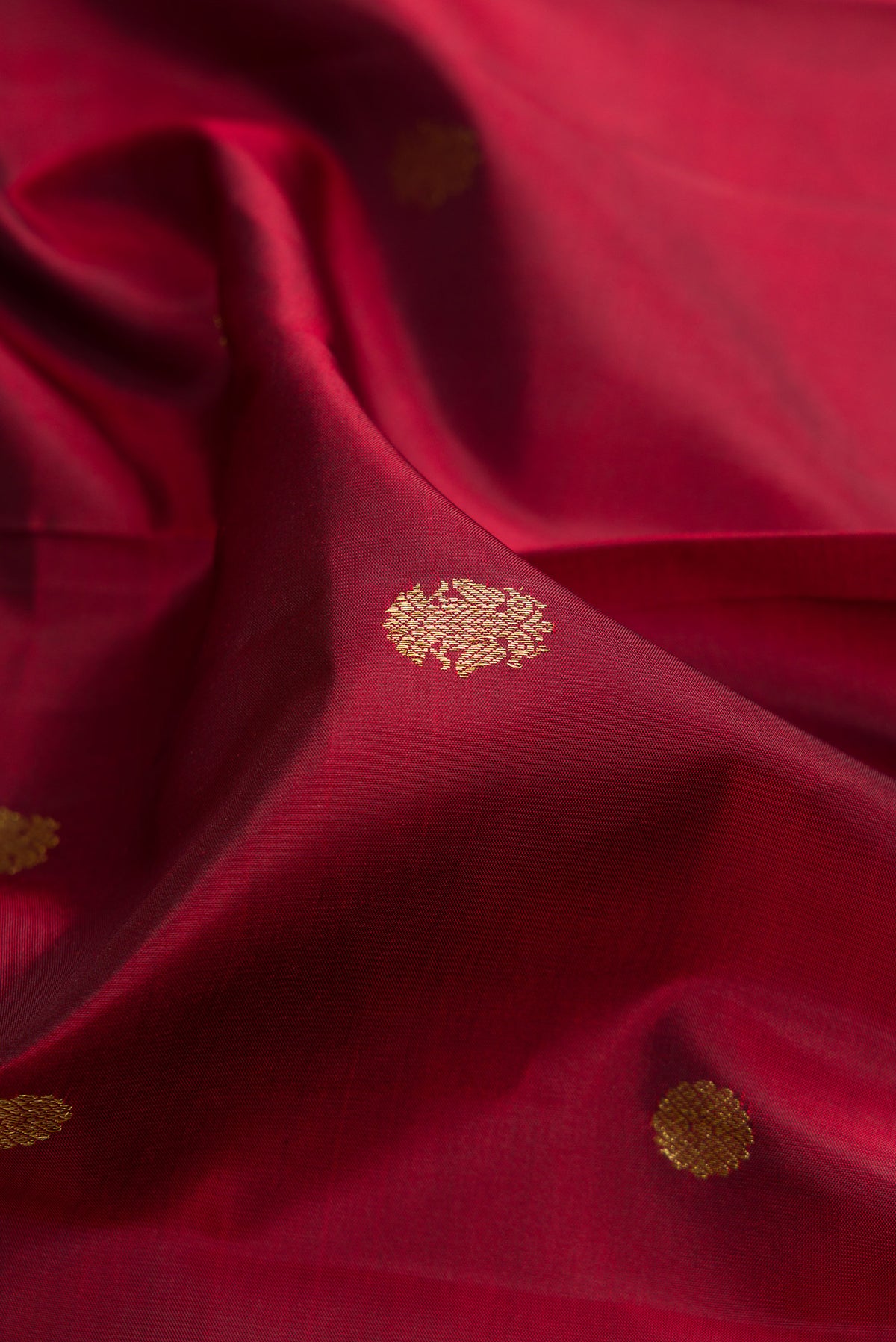 Close up of Pure Silk Maroon Kanjivaram Saree with Zari Butta on the body and Zari Border.  displaying folds