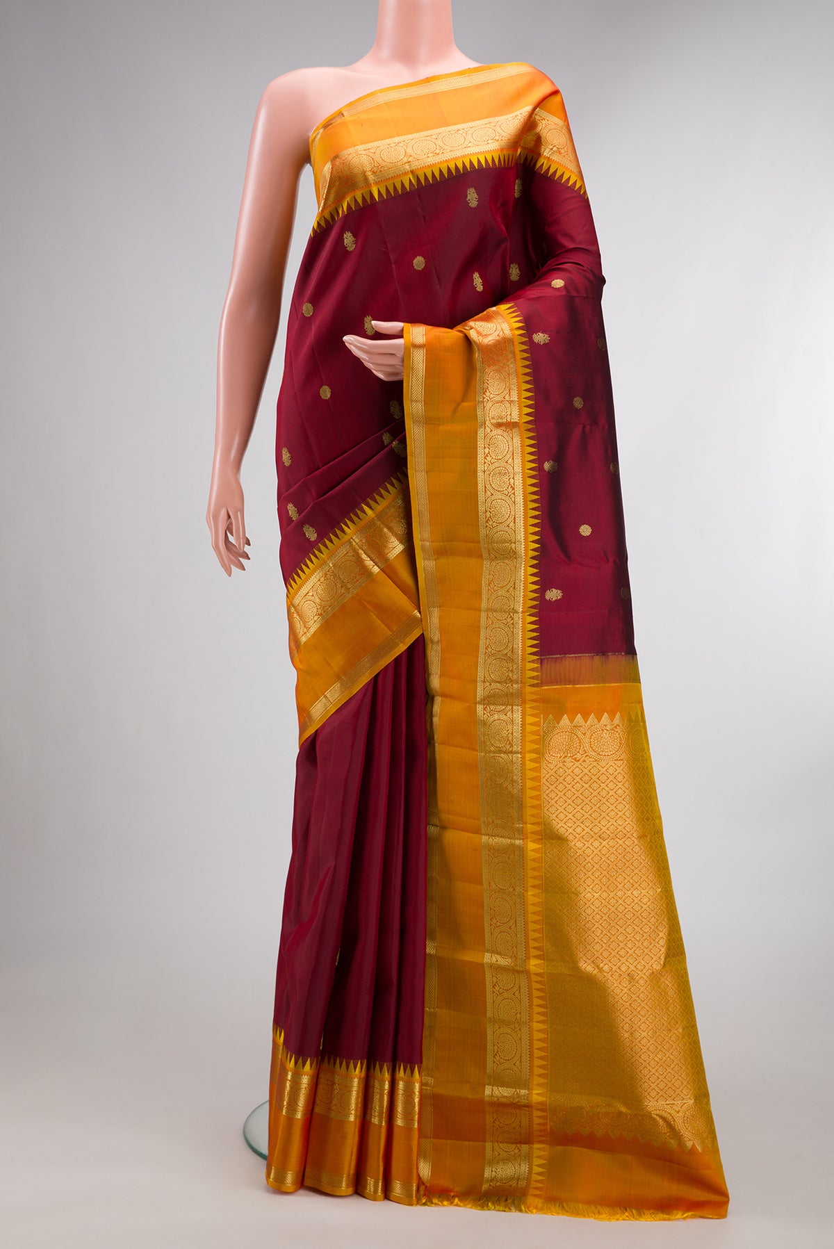 Pure Silk Maroon Kanjivaram Saree with Zari Butta on the body and Zari Border.  displayed on a mannequin