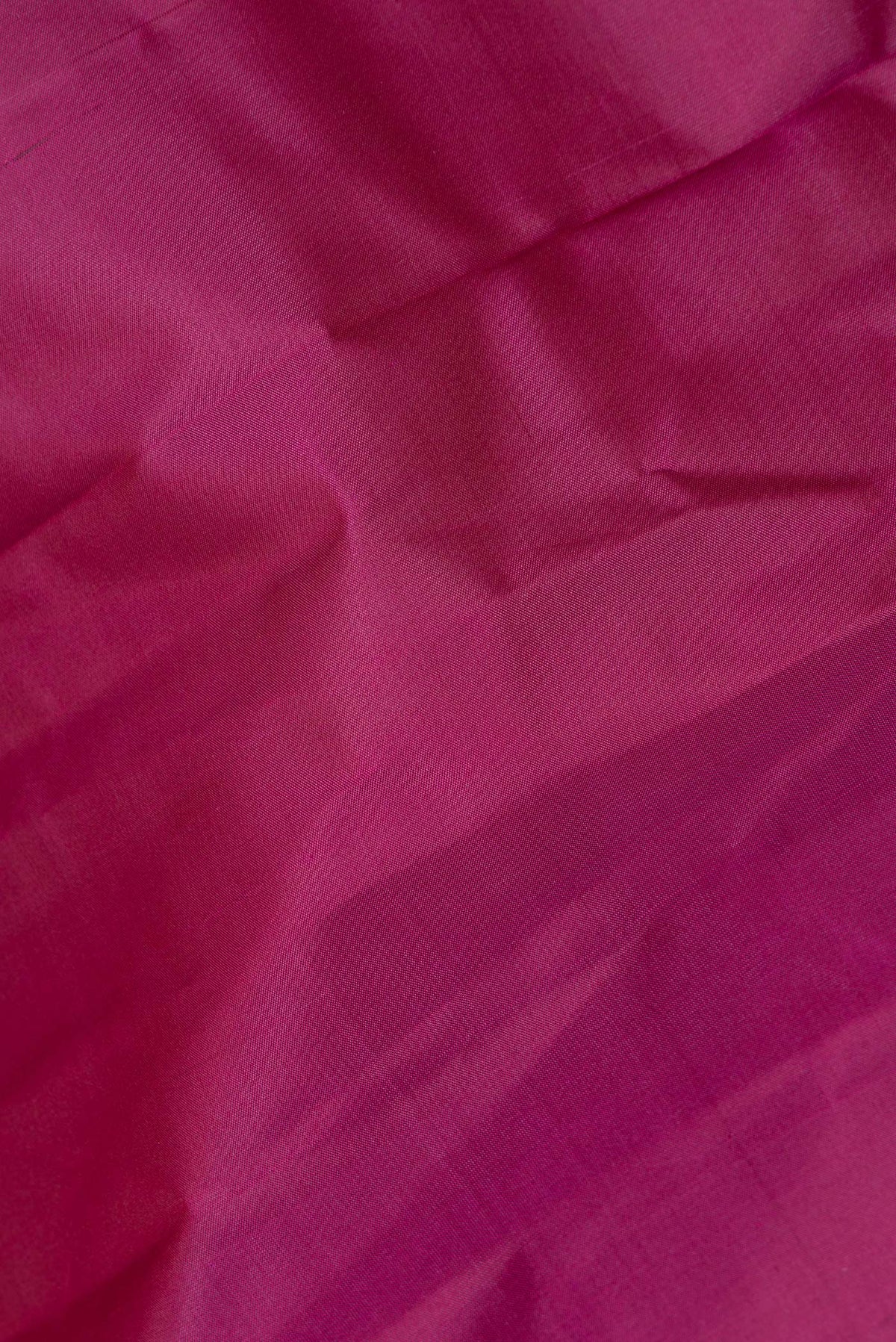 Close up of Pure Silk Magenta Dual Tone Kanchipuram Saree with Plain Body and Zari Border.  displaying folds