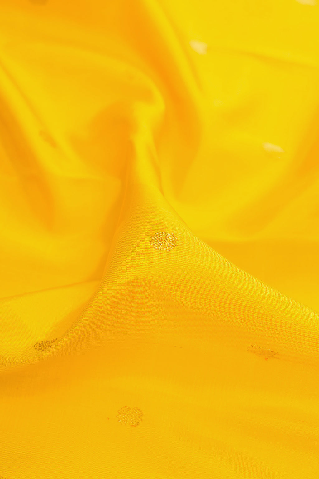 Close up of Pure Silk Yellow Kanchipuram Saree with Zari Butta on the body and Zari Border.  displaying folds