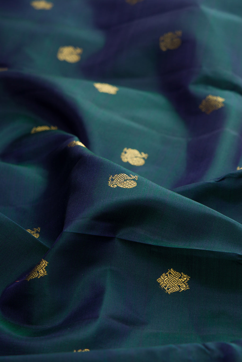 Close up of Pure Silk Pure Zari Peacock Blue Dual Tone Kanjivaram Saree with Zari Butta on the body and Zari Border.  displaying folds