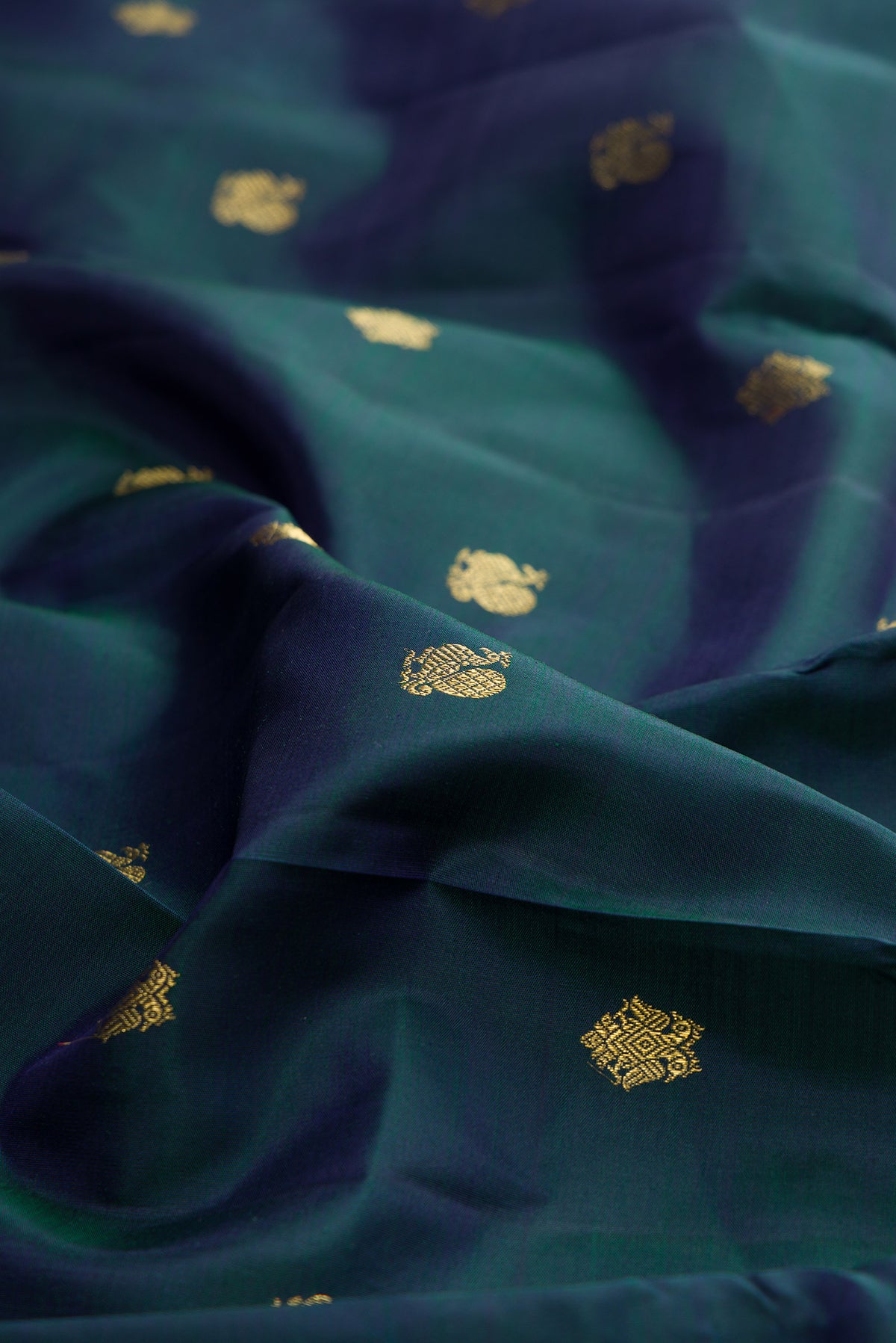 Close up of Pure Silk Pure Zari Peacock Blue Dual Tone Kanjivaram Saree with Zari Butta on the body and Zari Border.  displaying folds
