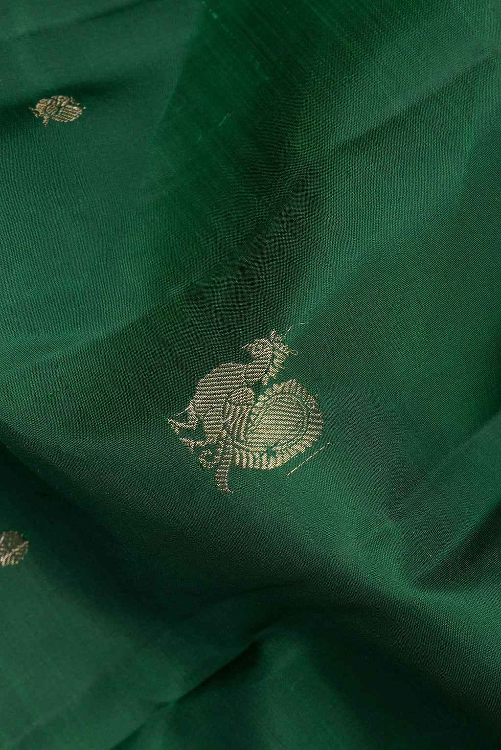 Close up of Pure Silk Bottle Green Kanjivaram Saree with Zari Butta on the body and Zari Border.  displaying folds