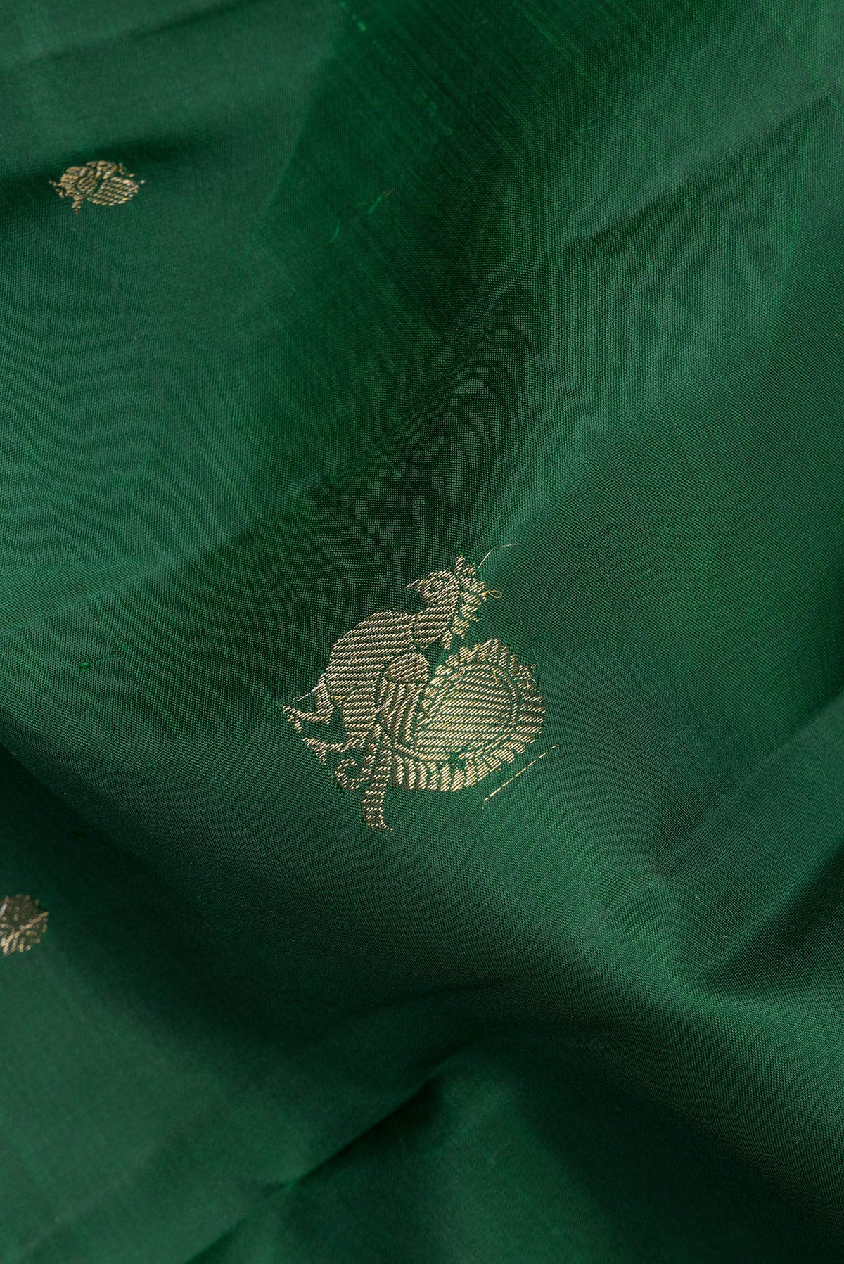 Close up of Pure Silk Bottle Green Kanjivaram Saree with Zari Butta on the body and Zari Border.  displaying folds