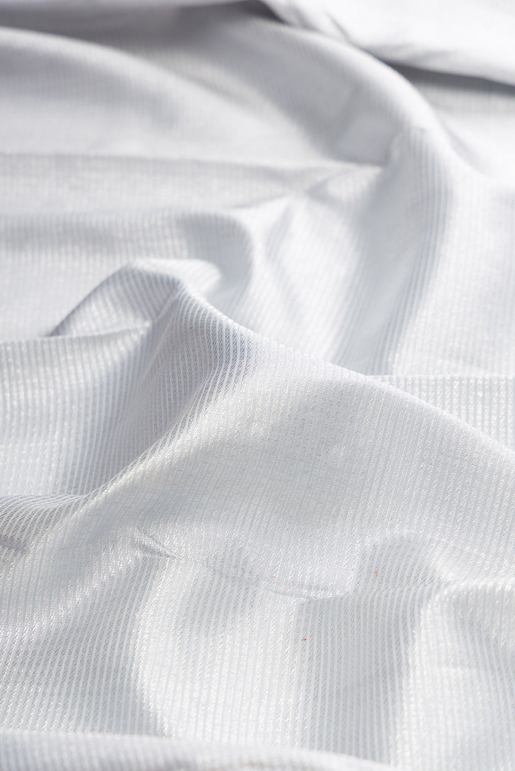 Close up of Pure Silk Silver Kanchipuram Saree with Zari Brocade on the body and Zari Border.  displaying folds