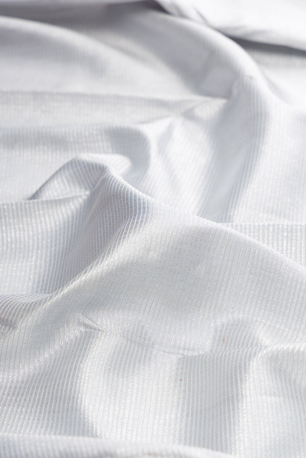Close up of Pure Silk Silver Kanchipuram Saree with Zari Brocade on the body and Zari Border.  displaying folds