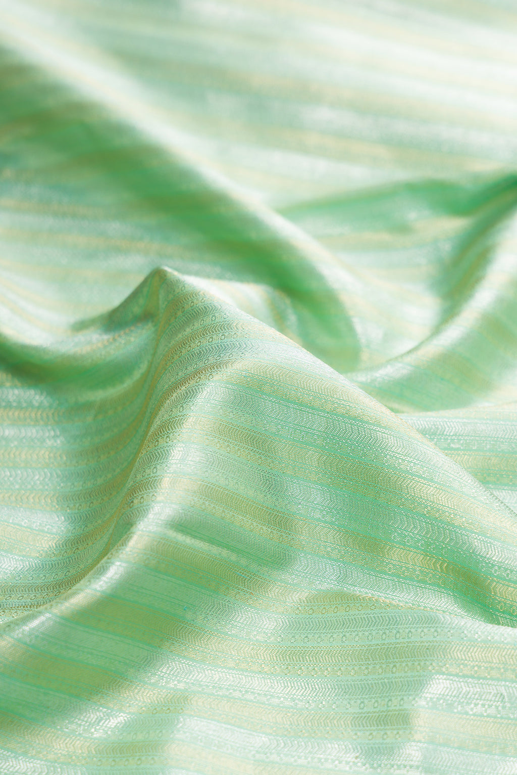 Close up of Pure Silk Pista Green Kanchipuram Saree with Zari Brocade on the body and Zari Border.  displaying folds
