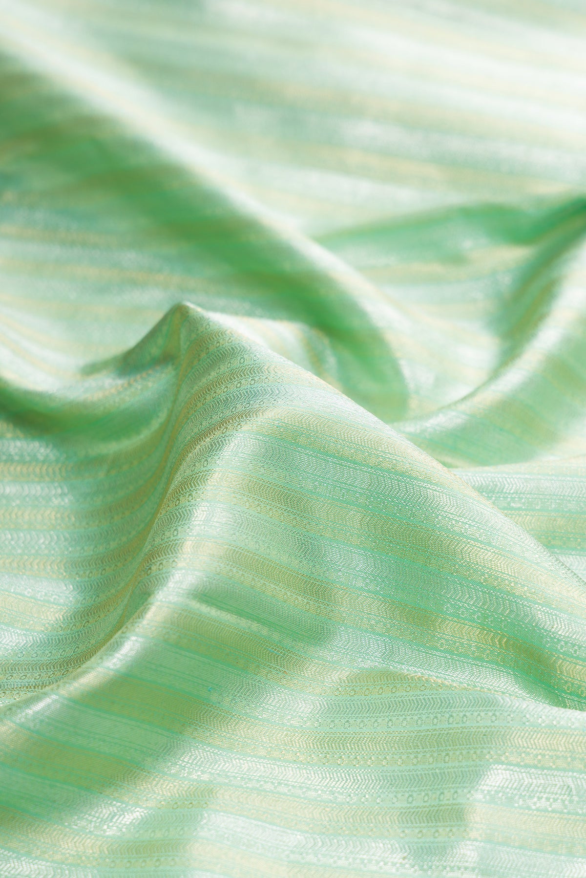 Close up of Pure Silk Pista Green Kanchipuram Saree with Zari Brocade on the body and Zari Border.  displaying folds