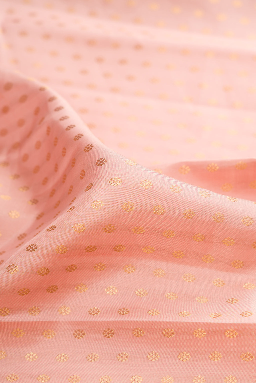 Close up of Pure Silk Golden Peach Kanjivaram Saree with Zari Butta on the body and Zari Border.  displaying folds
