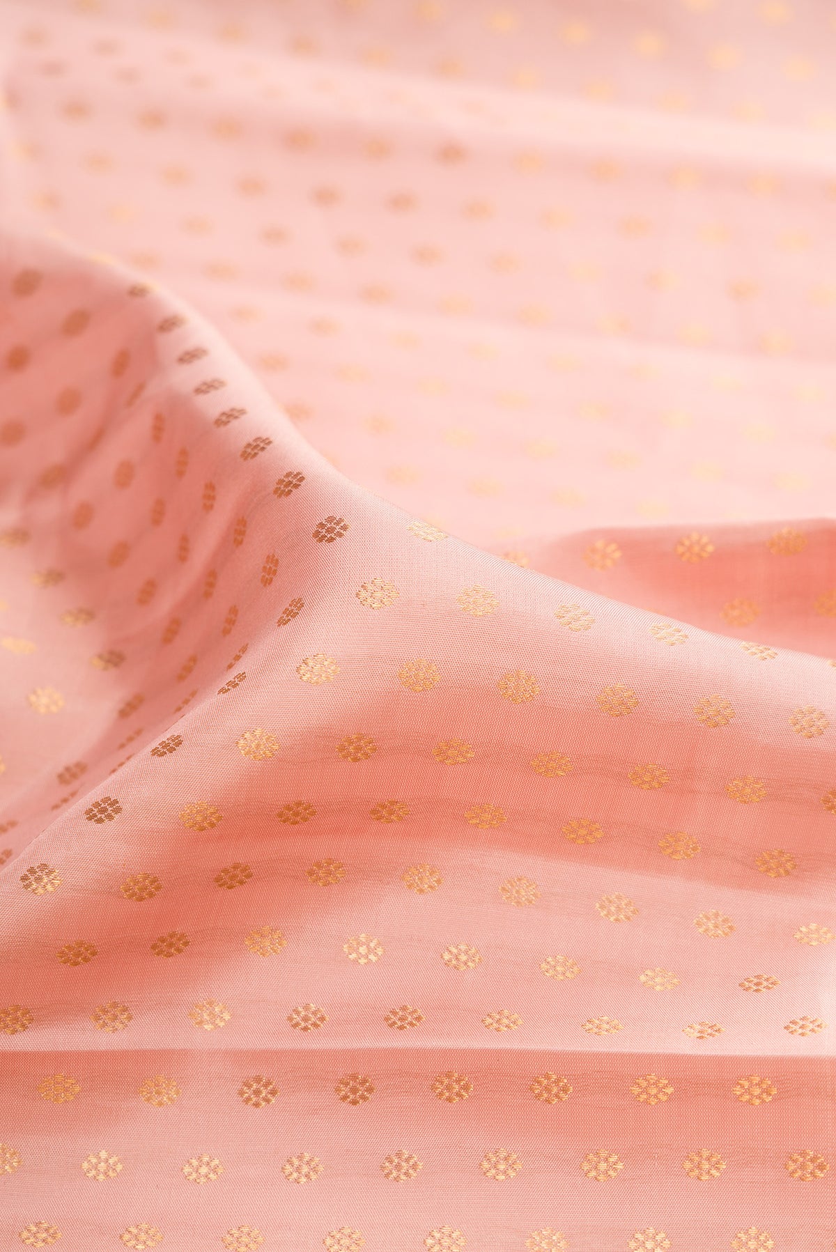 Close up of Pure Silk Golden Peach Kanjivaram Saree with Zari Butta on the body and Zari Border.  displaying folds