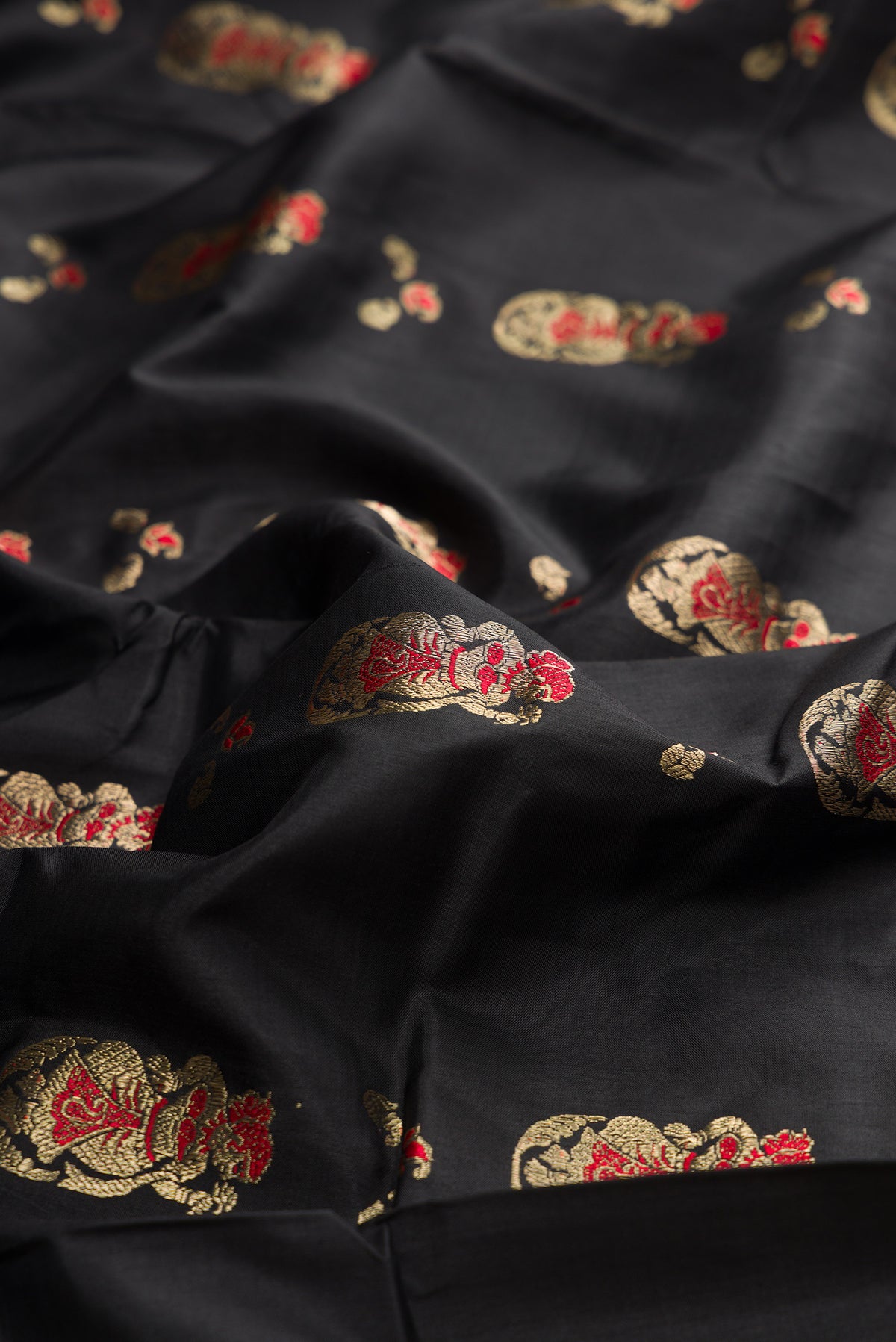 Close up of Pure Silk Black Baluchari Saree with Zari And Thread Butta on the body and Fancy Border.  displaying folds
