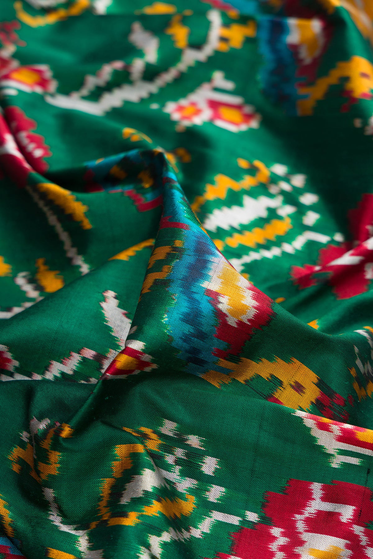 Close up of Pure Silk Bottle Green Dual Tone Double Ikat Saree with Ikat Print on the body and Ikat Border.  displaying folds