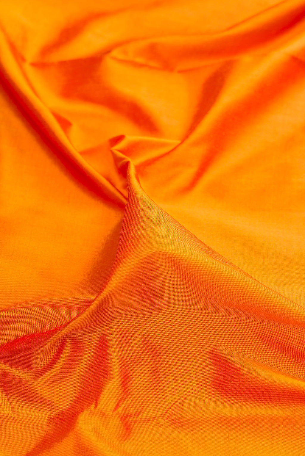 Close up of Pure Silk Orange Dual Tone Double Ikat Saree with Plain Body and Ikat Border.  displaying folds