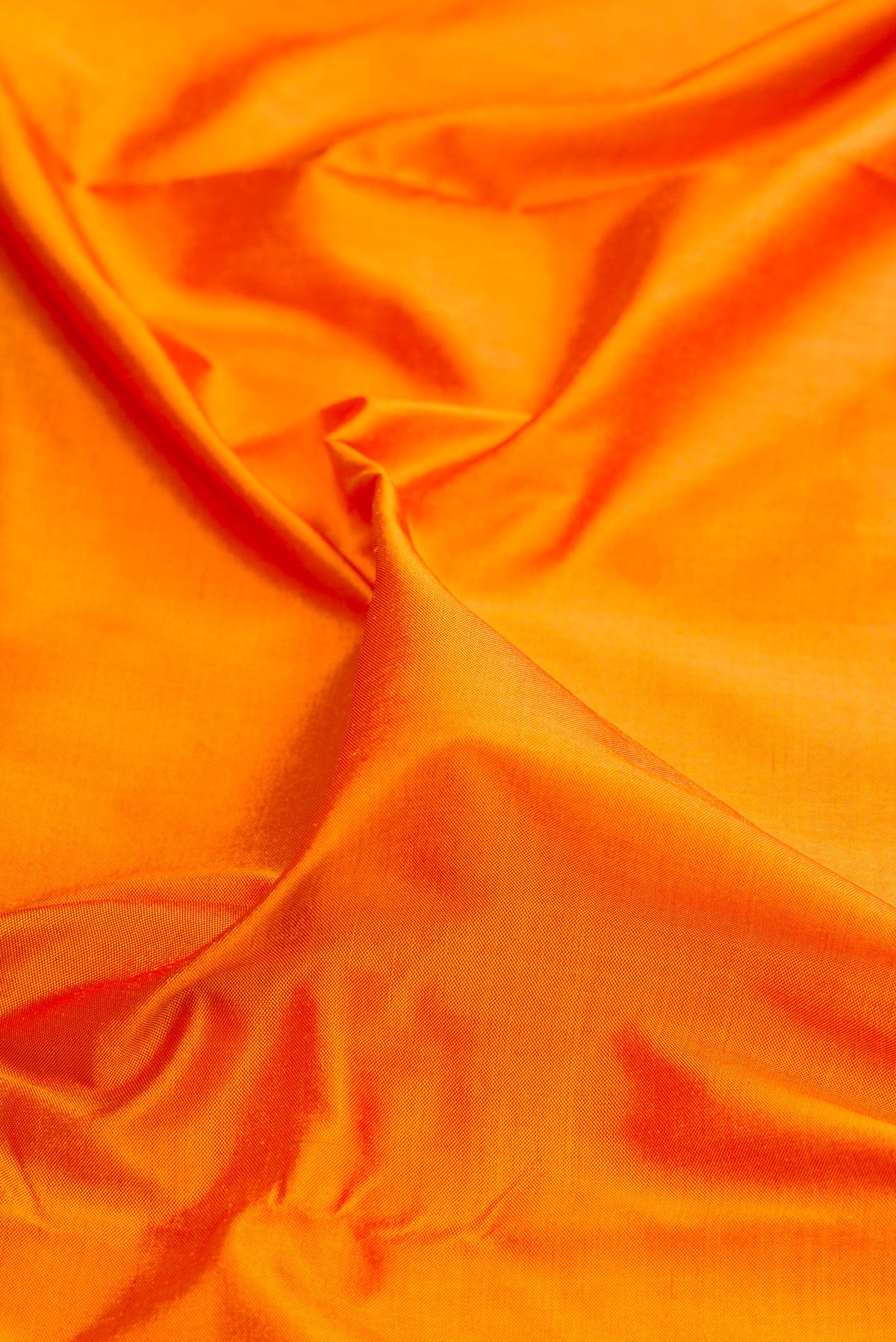 Close up of Pure Silk Orange Dual Tone Double Ikat Saree with Plain Body and Ikat Border.  displaying folds