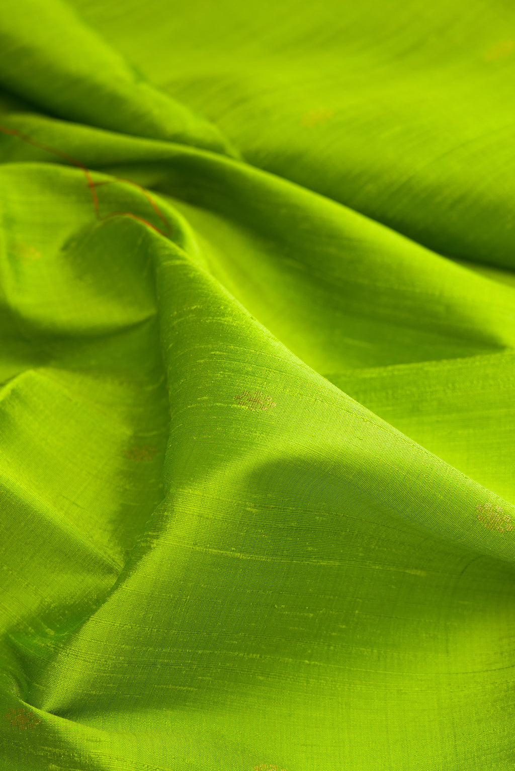 Close up of Parrot Green Raw Saree with Zari Butta on the body and Zari Border.  displaying folds