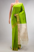 Parrot Green Raw Saree with Zari Butta on the body and Zari Border.  displayed on a mannequin