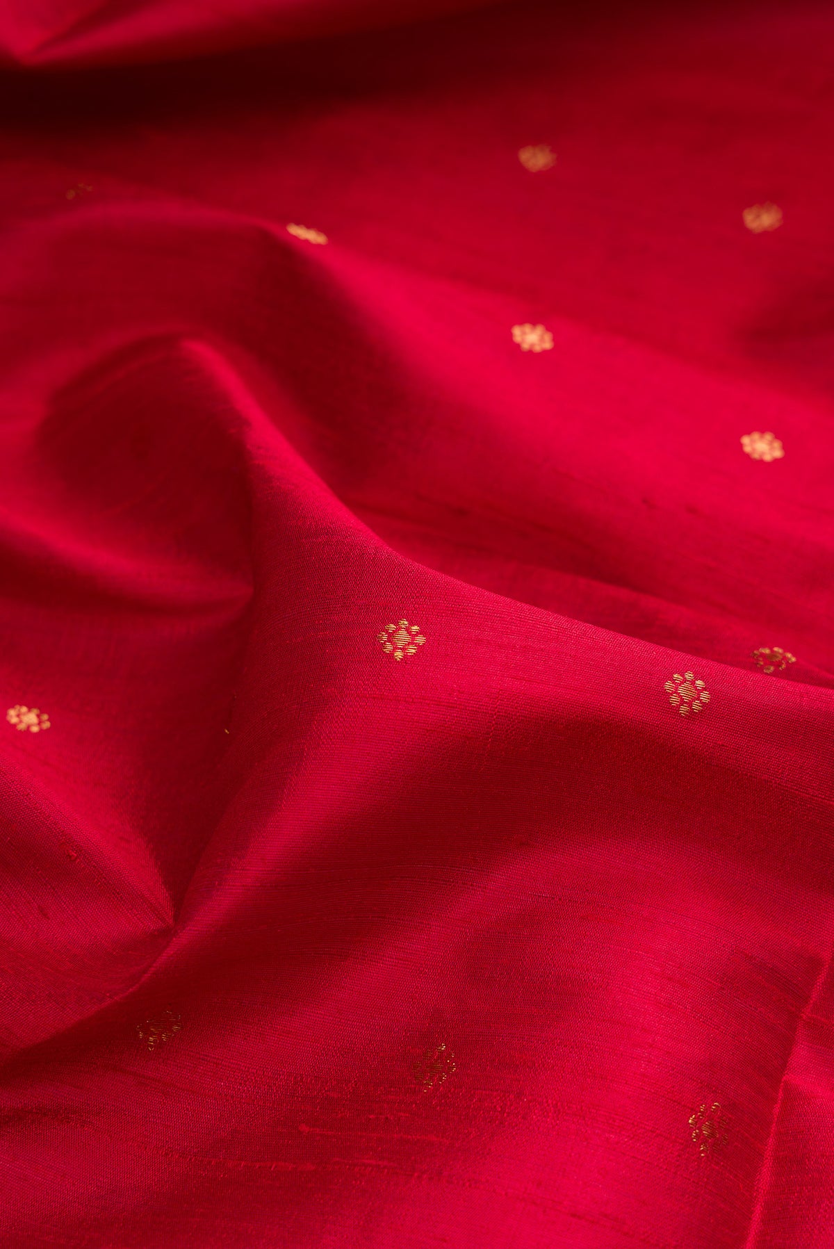 Close up of Deep Red Raw Saree with Zari Butta on the body and Zari Border.  displaying folds