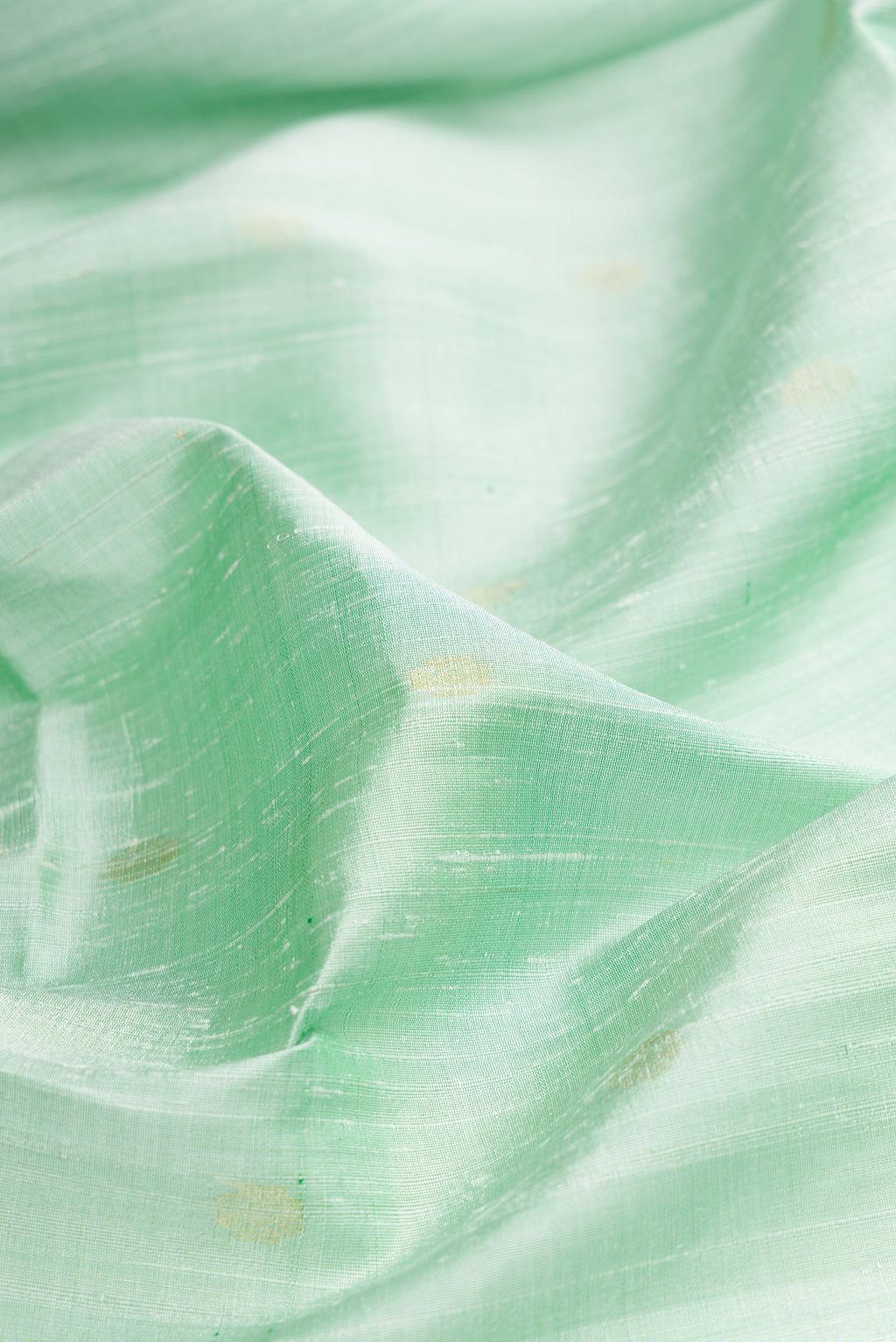 Close up of Pista Green Raw Saree with Zari Butta on the body and Zari Border.  displaying folds