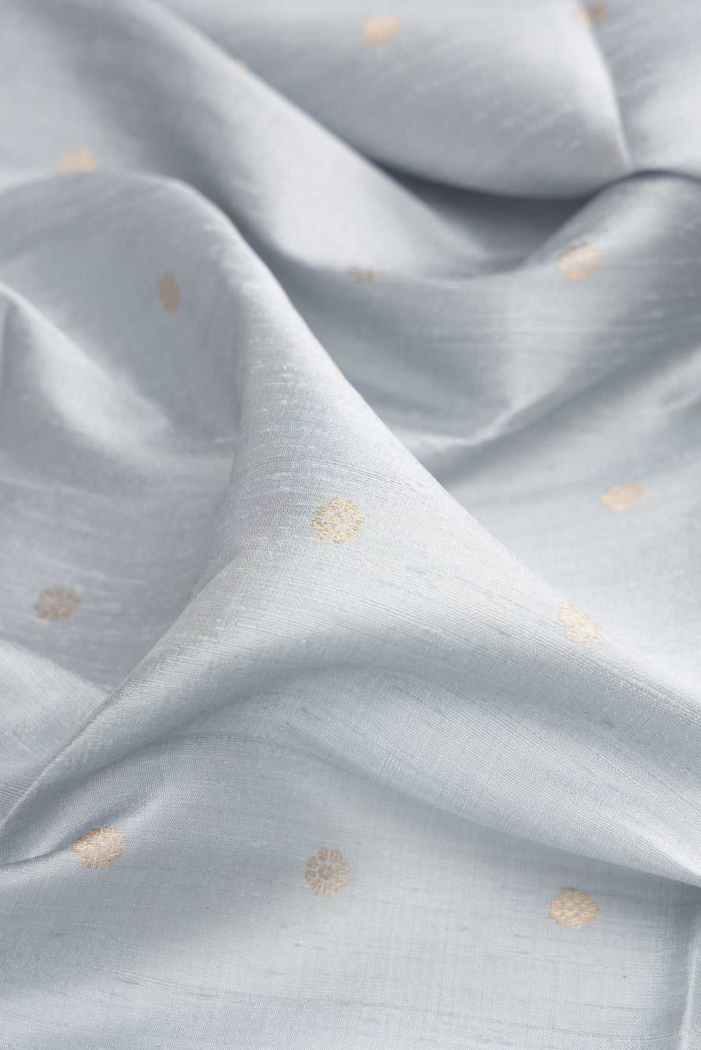 Close up of Light Blue Raw Saree with Zari Butta on the body and Zari Border.  displaying folds