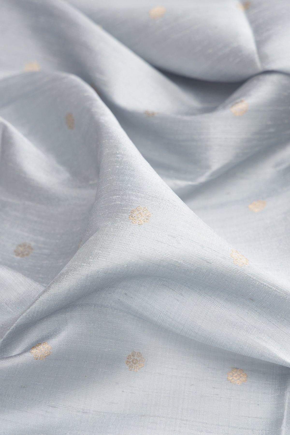 Close up of Light Blue Raw Saree with Zari Butta on the body and Zari Border.  displaying folds