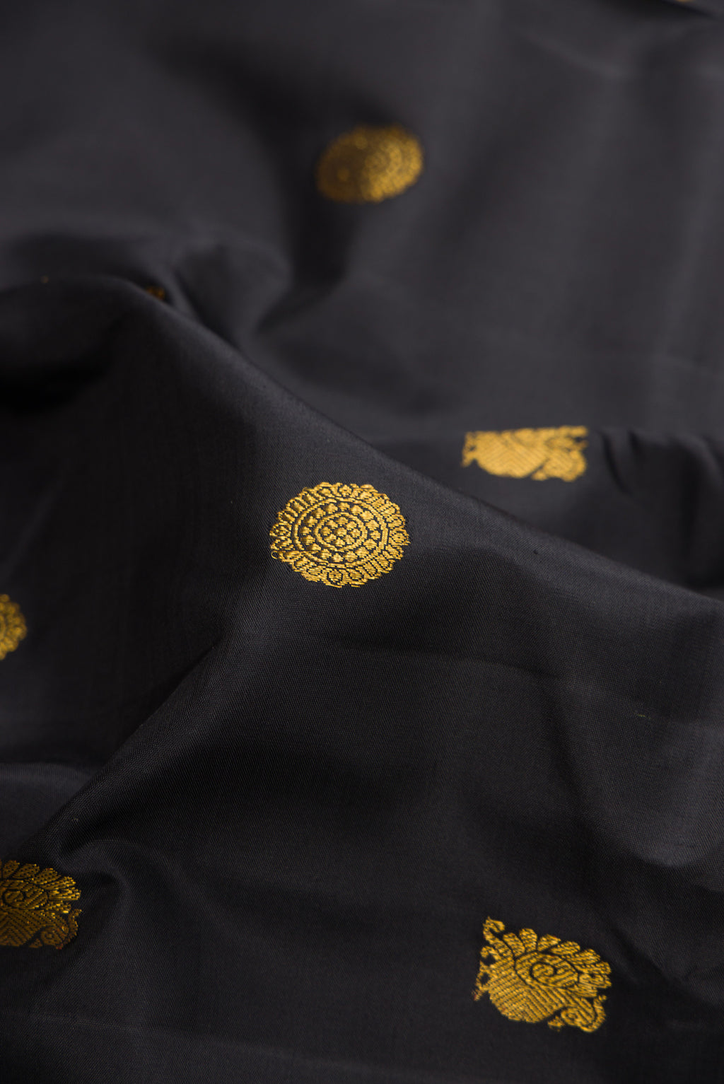 Close up of Pure Silk Black Kanjivaram Saree with Zari Butta on the body and Zari Border.  displaying folds
