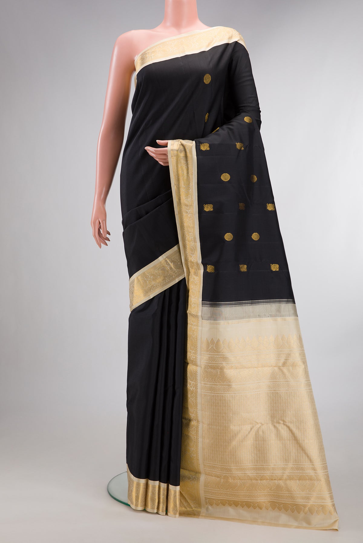 Pure Silk Black Kanjivaram Saree with Zari Butta on the body and Zari Border.  displayed on a mannequin