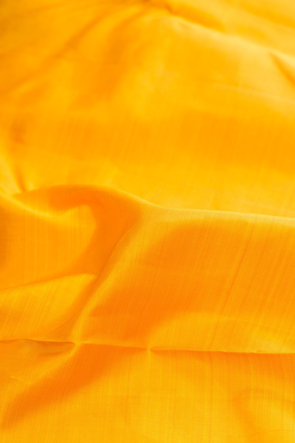 Close up of Pure Silk Pure Zari Yellow Dual Tone Kanjivaram Saree with Plain Body and One Side Border.  displaying folds