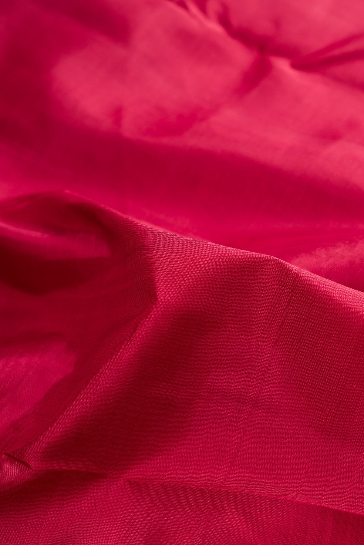 Close up of Pure Silk Pure Zari Deep Red Kanjivaram Saree with Plain Body and One Side Border.  displaying folds