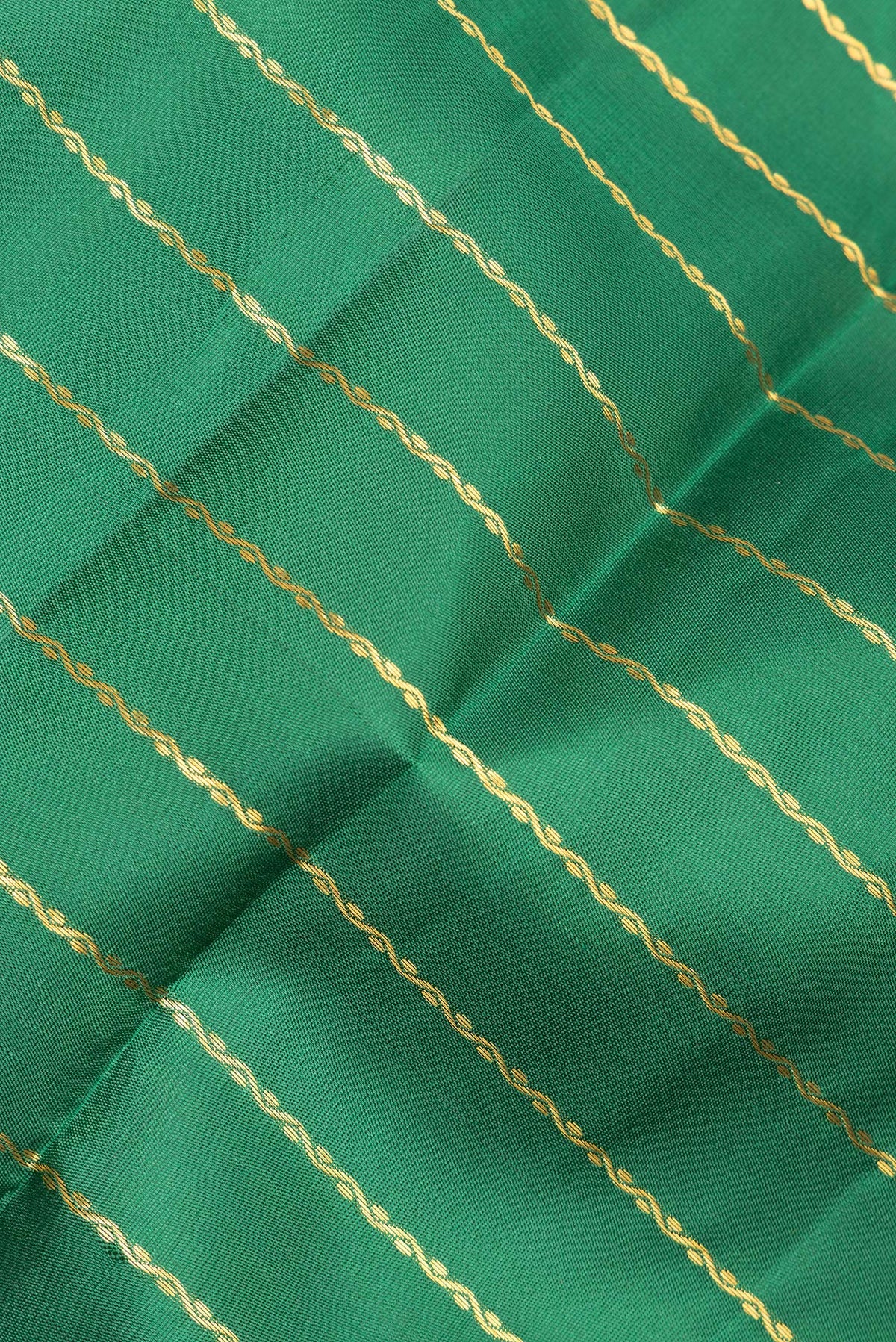 Close up of Pure Silk Bottle Green Kanchipuram Saree with Veldhari on the body and Zari Border.  displaying folds