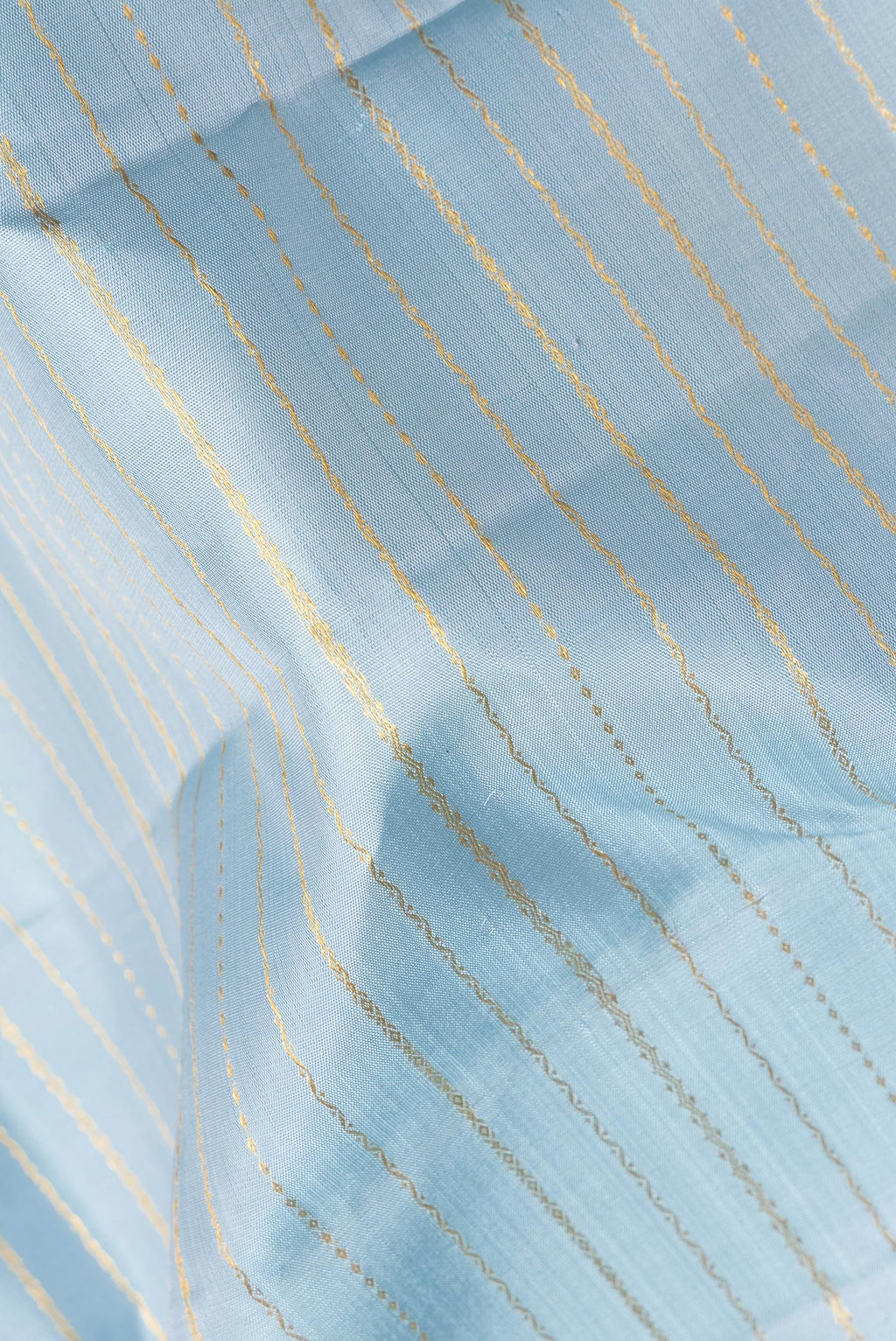 Close up of Pure Silk Light Blue Kanjivaram Saree with Veldhari on the body and Zari Border.  displaying folds