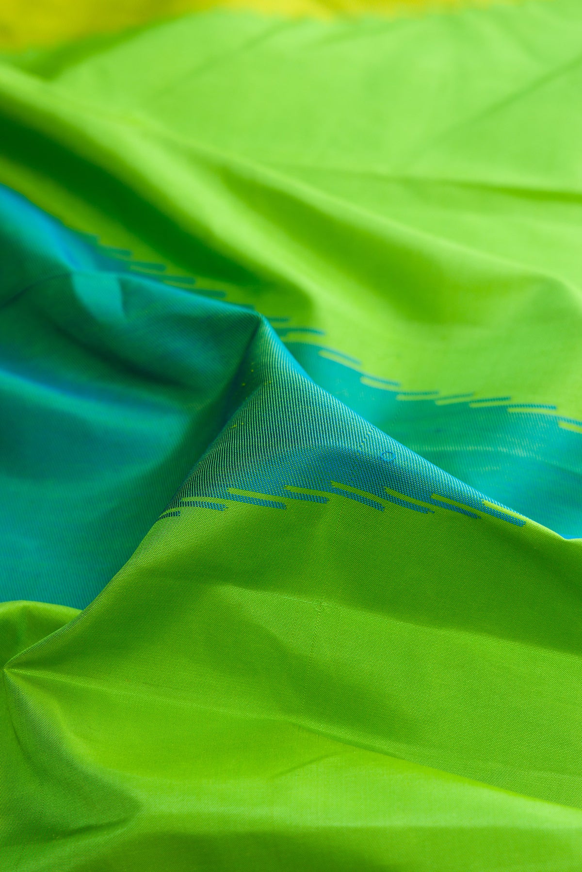 Close up of Pure Silk Parrot Green Dual Tone Kanjivaram Saree with Plain Body and Temple Border.  displaying folds