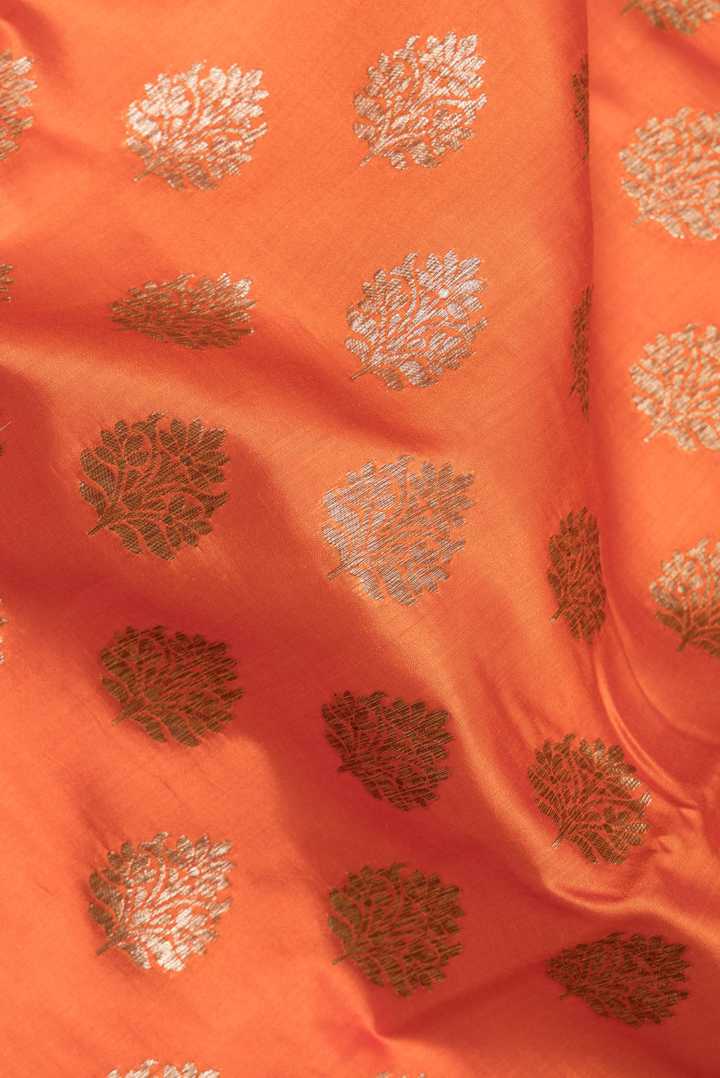 Close up of Orange Raw Saree with Zari Butta on the body and Zari Border.  displaying folds