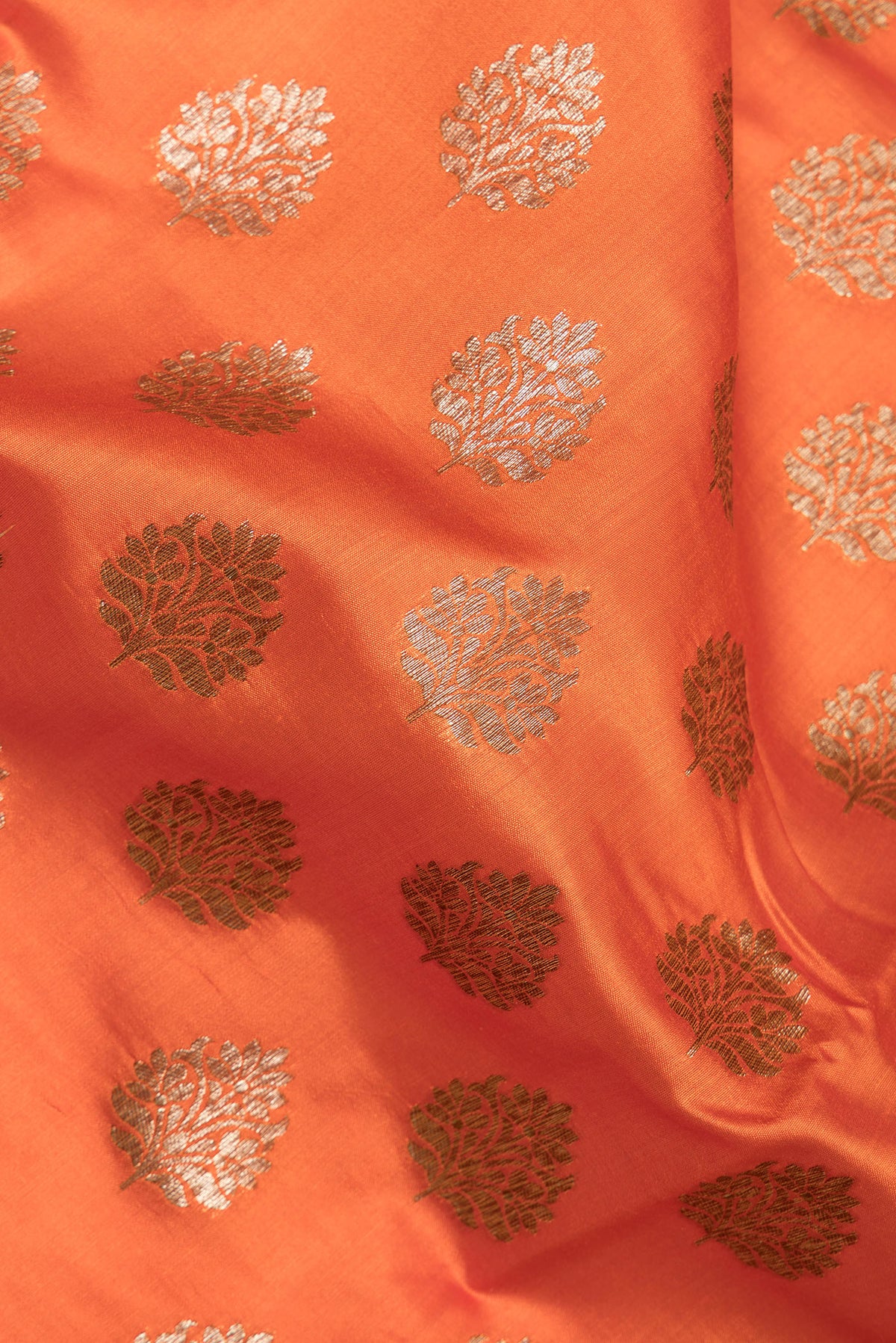 Close up of Orange Raw Saree with Zari Butta on the body and Zari Border.  displaying folds