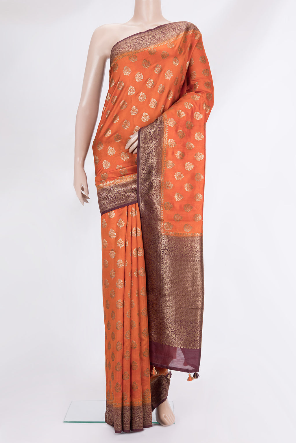 Orange Raw Saree with Zari Butta on the body and Zari Border.  displayed on a mannequin