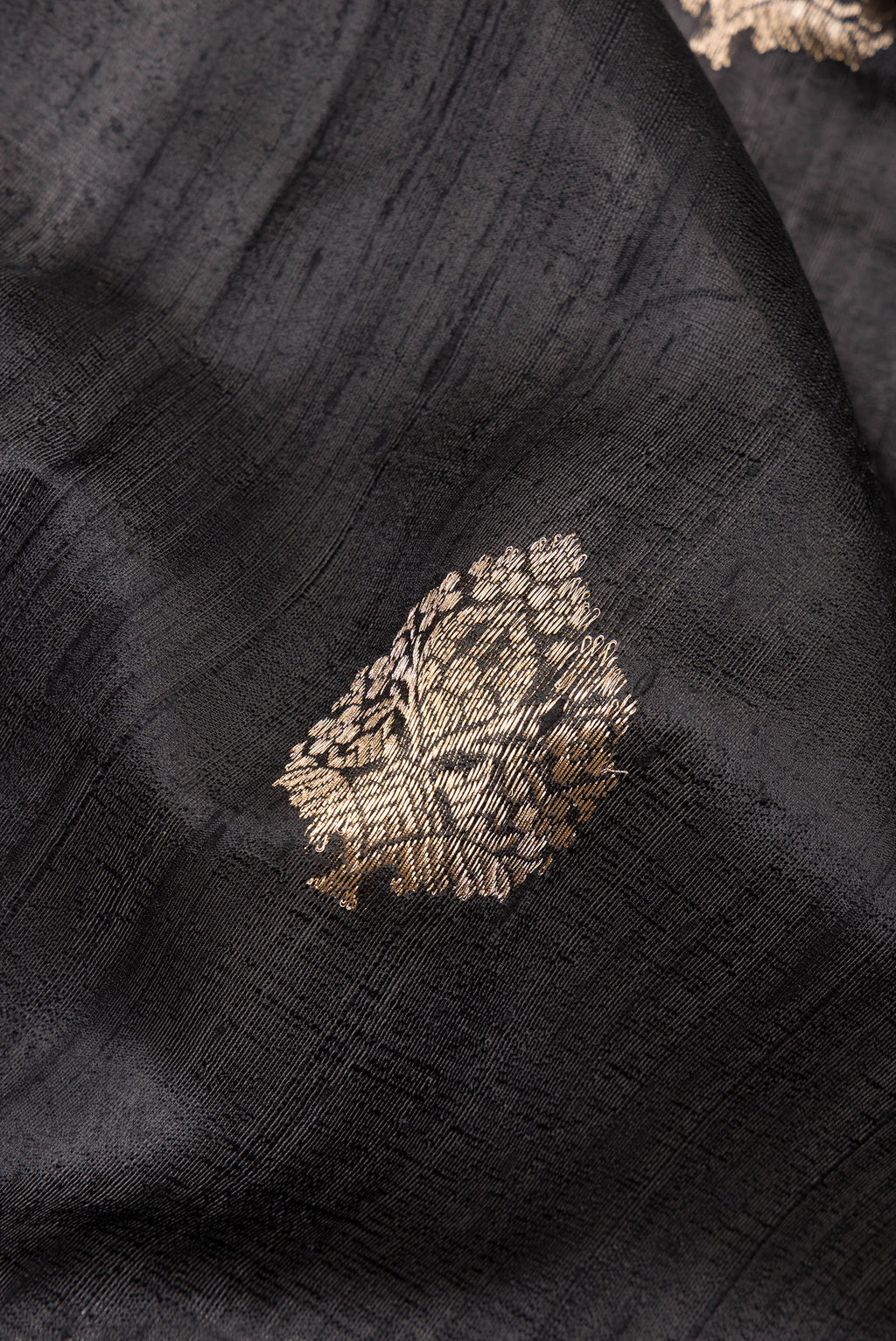 Close up of Pure Silk Black Banarasi Tussar Saree with Zari Butta on the body and Zari Border.  displaying folds