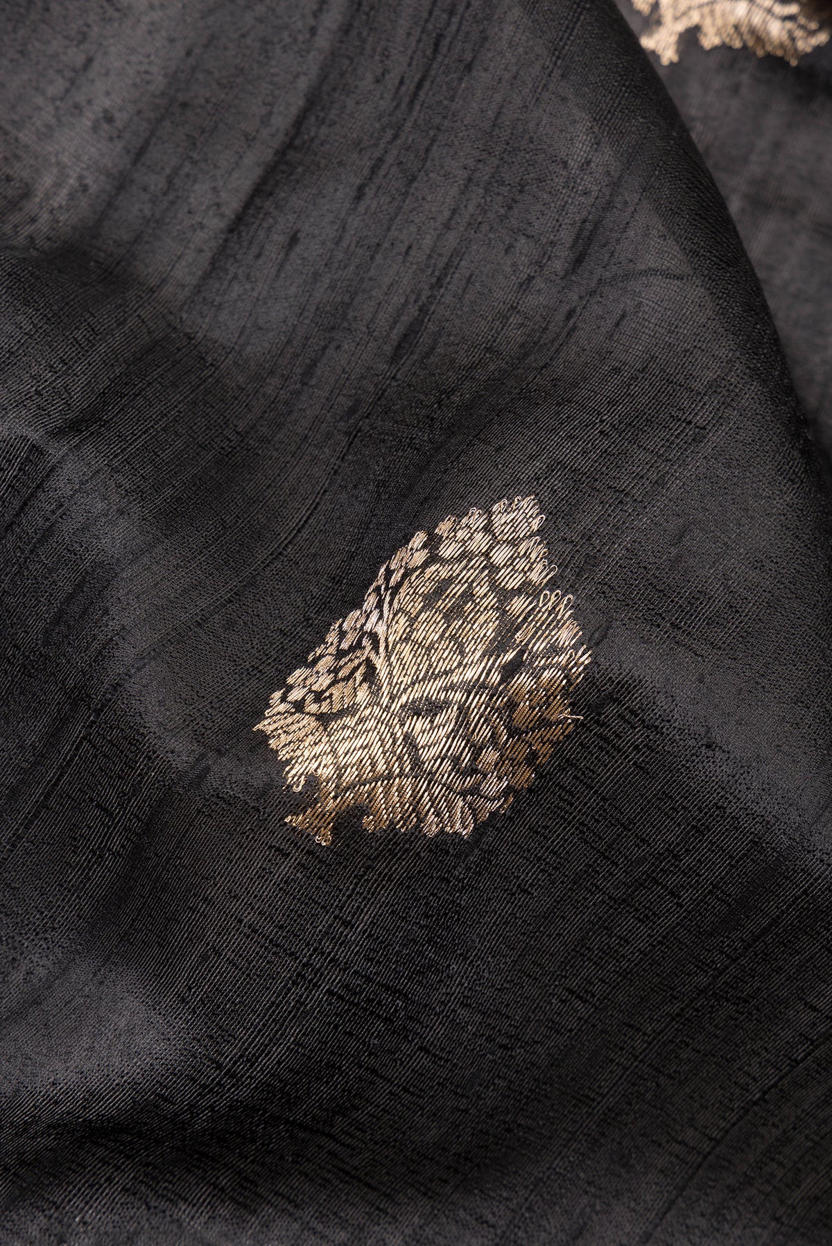 Close up of Pure Silk Black Banarasi Tussar Saree with Zari Butta on the body and Zari Border.  displaying folds